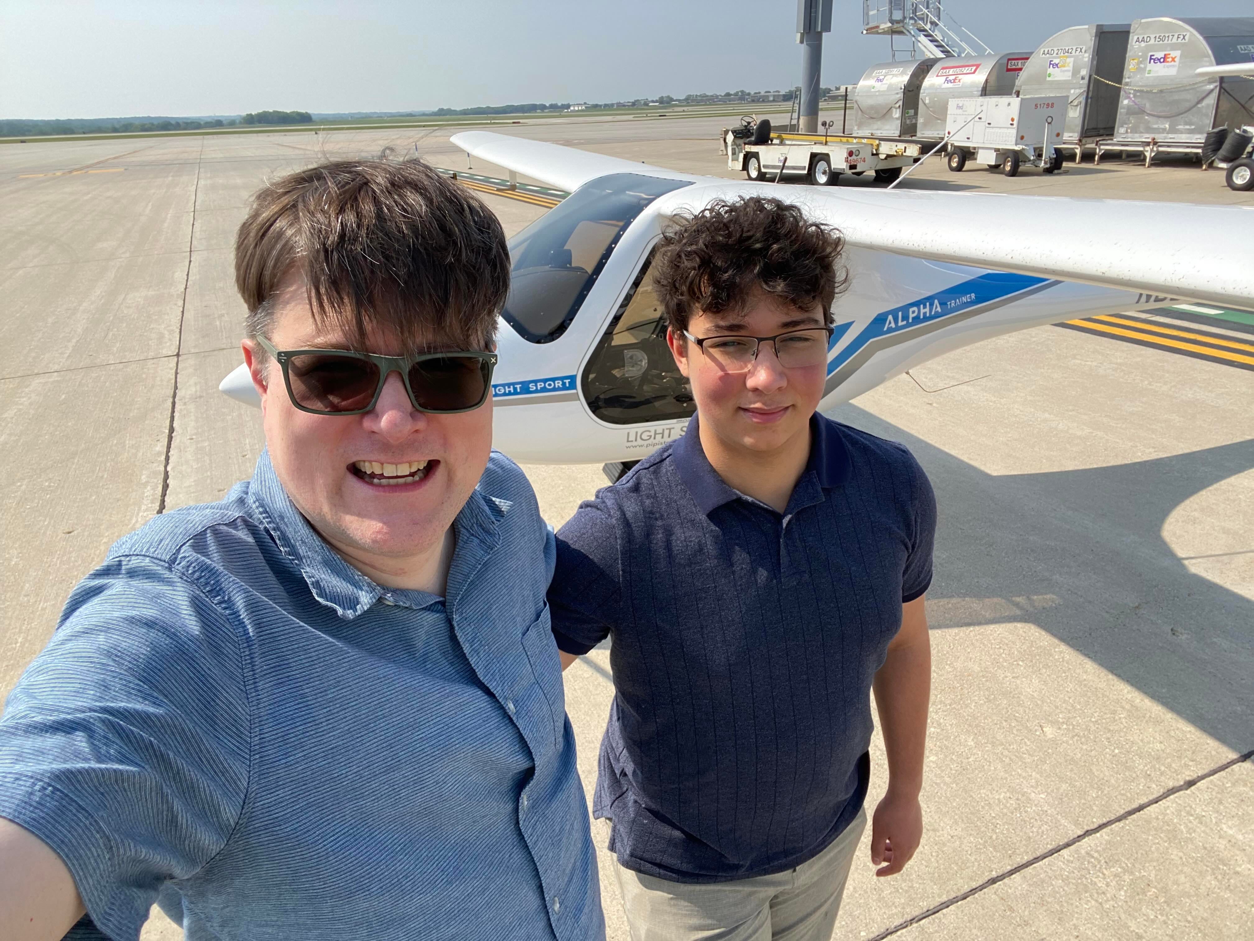 The author and his son stand on a tarmac in front of a small plane.