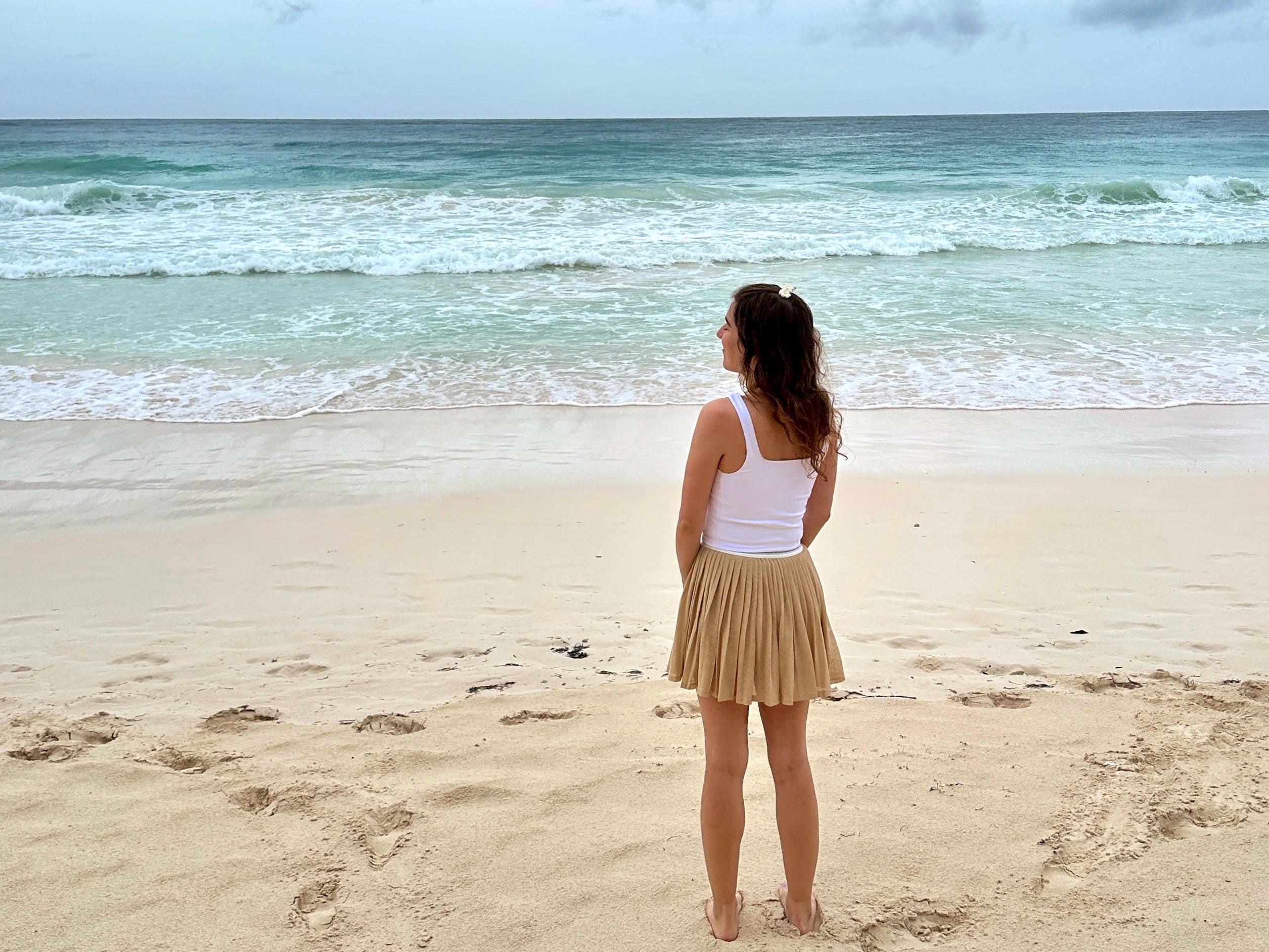 Author Rebecca Shinners staring out at water on beach