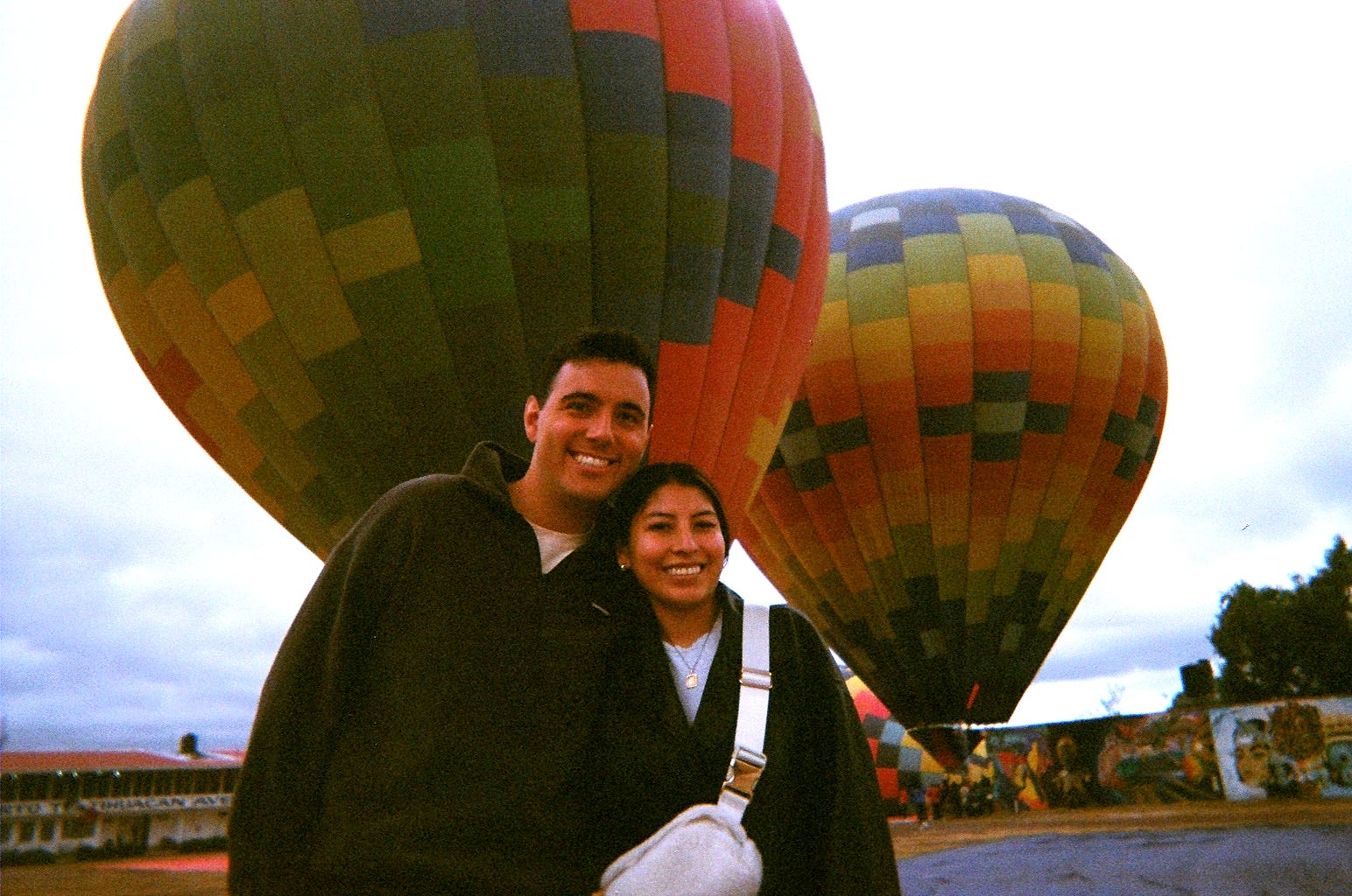 Viviana Vazquez and her fiancé smile as they stand in front of two hot air balloons
