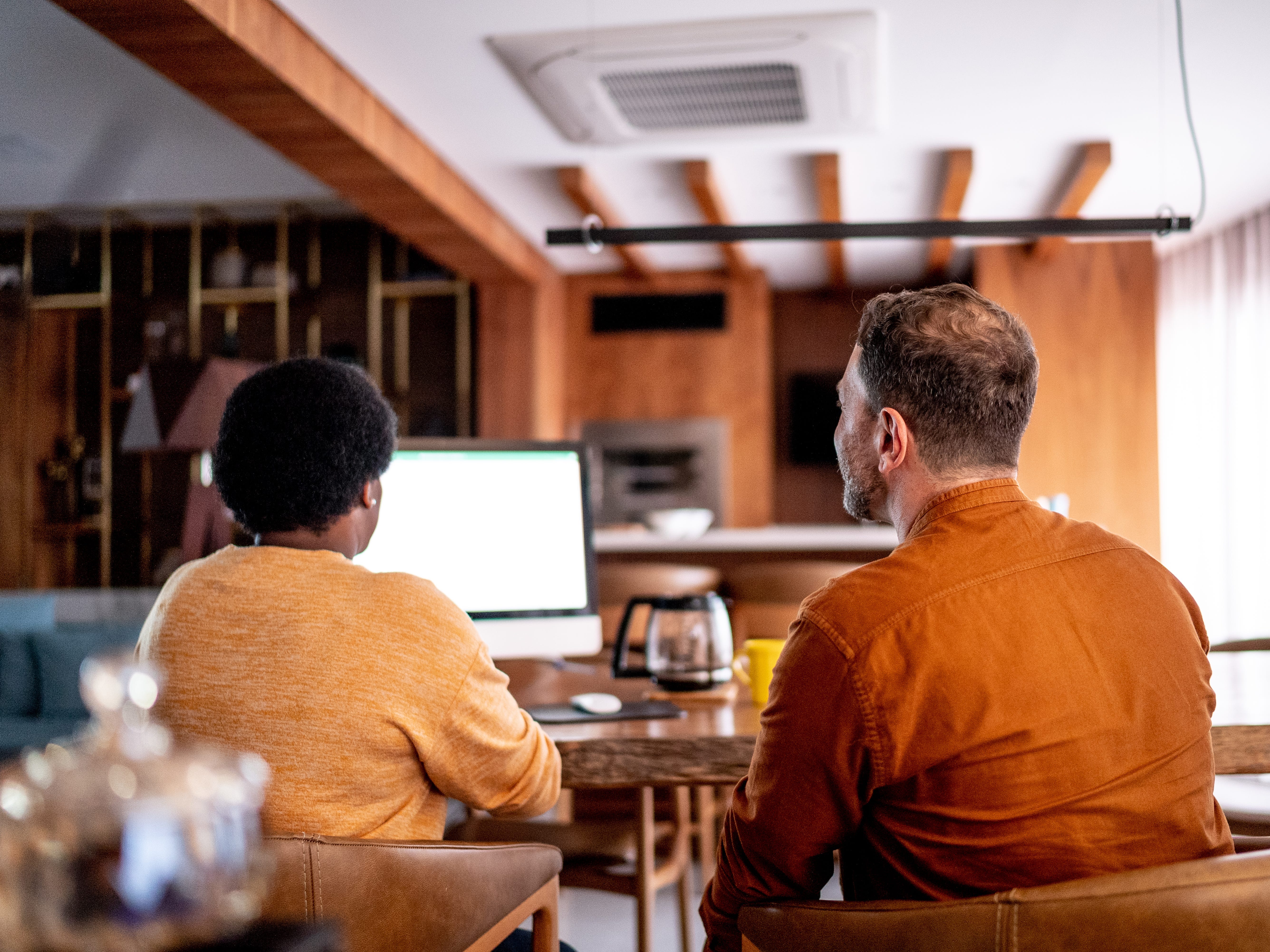 A couple looking at a computer while sitting at a desk.