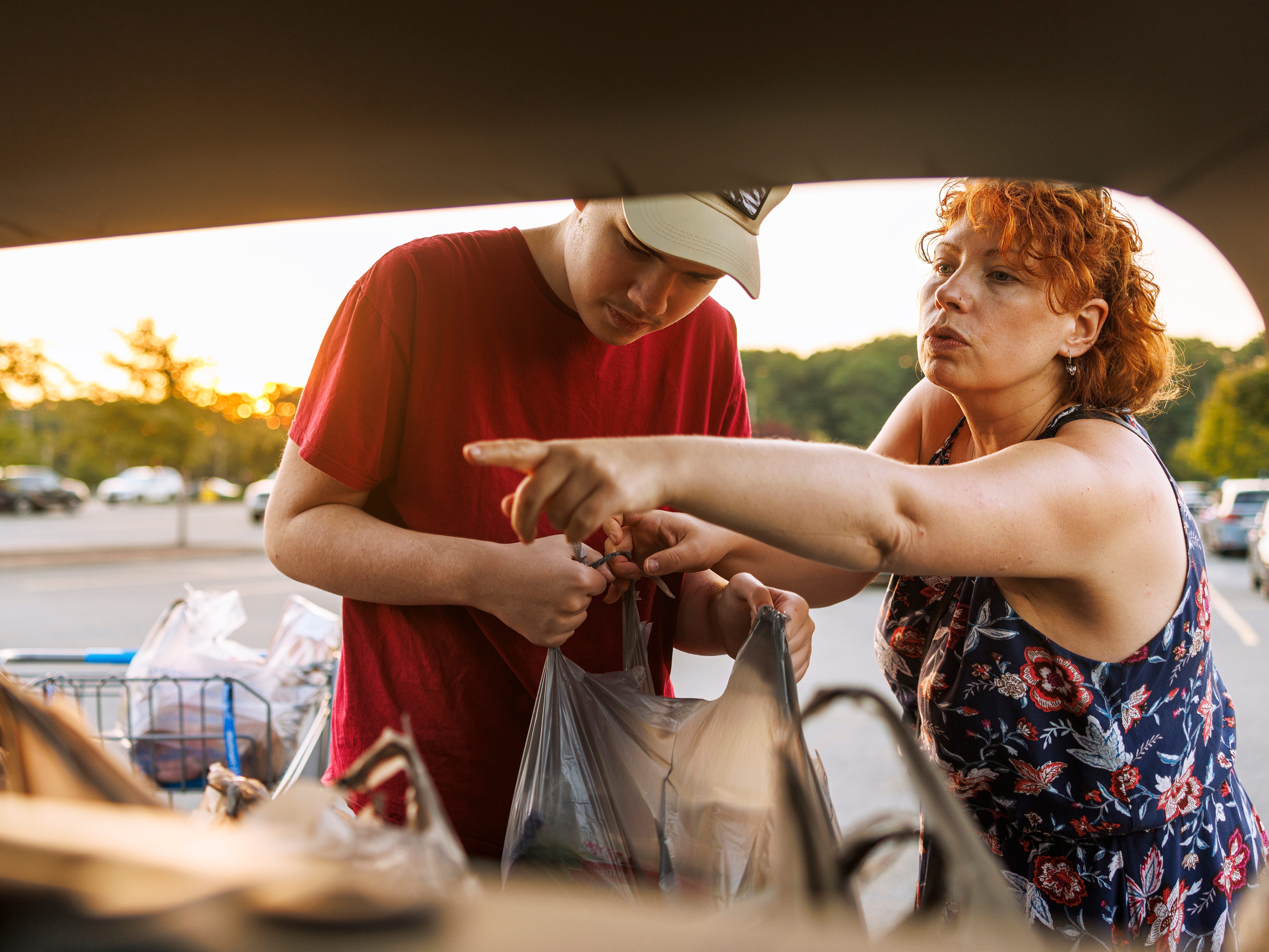 a woman and her son loading the trunk of her car with groceries