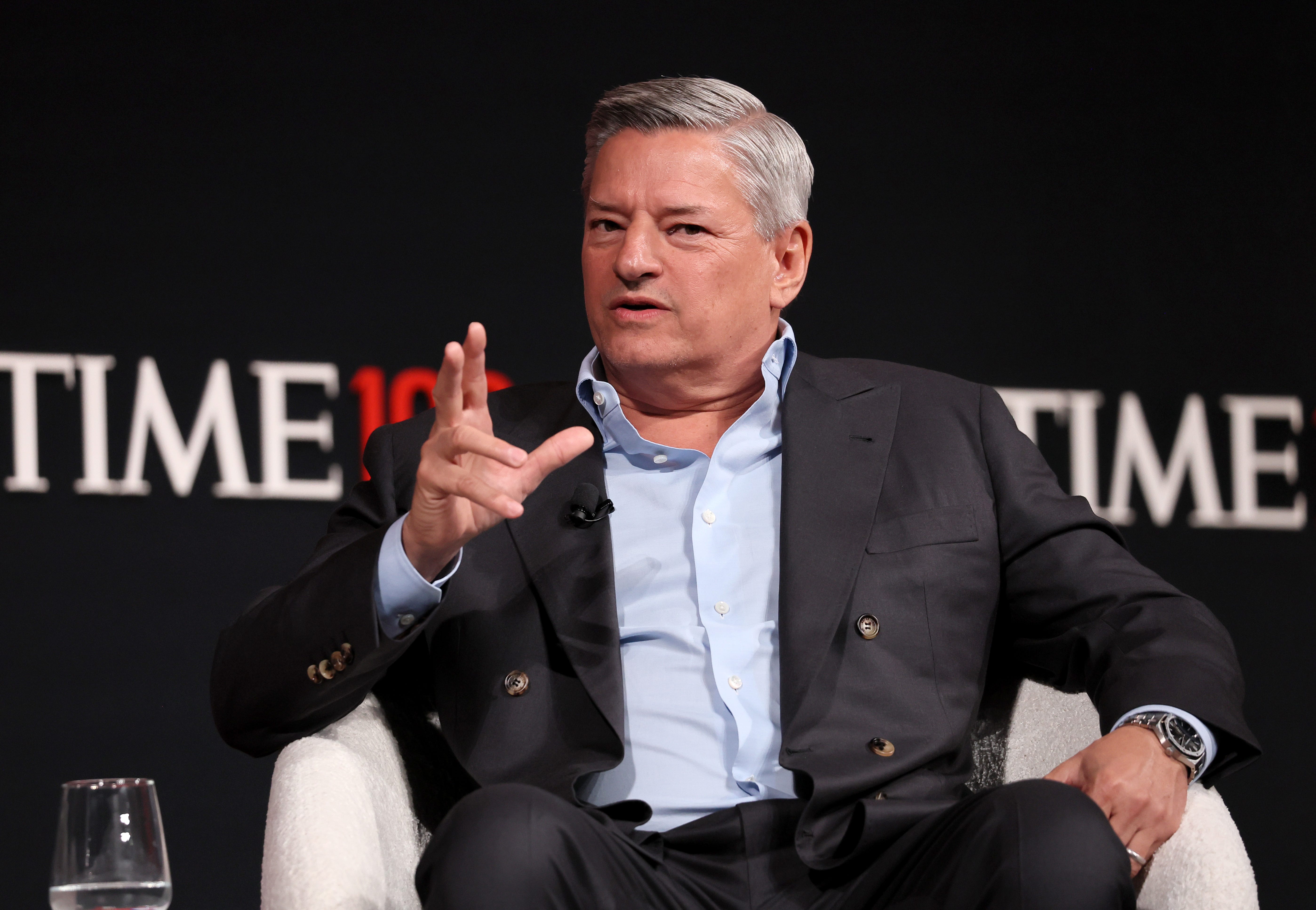 Ted Sarandos in a dark suit sitting on a chair