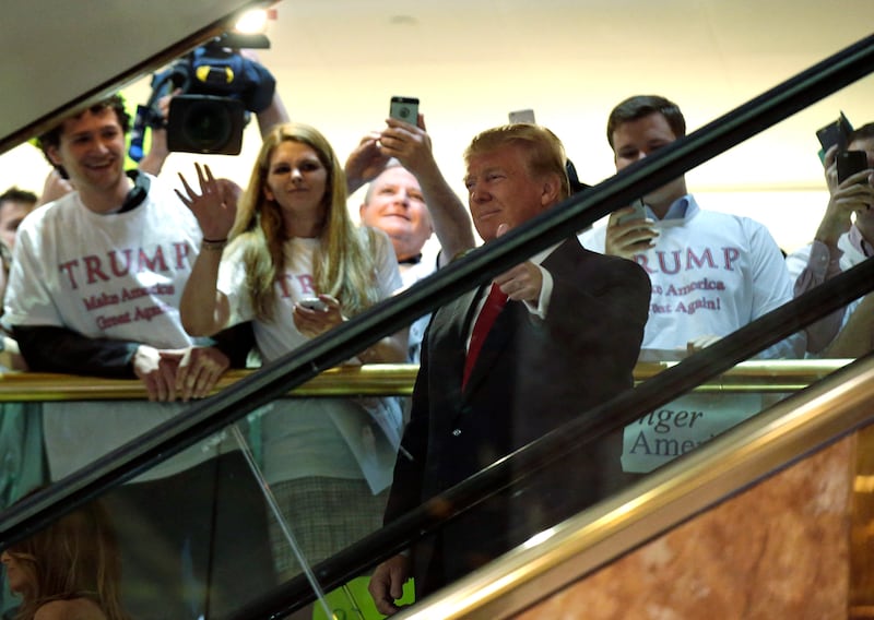 Donald Trump arrives by escalator inside Trump Tower giving a thumbs up sign