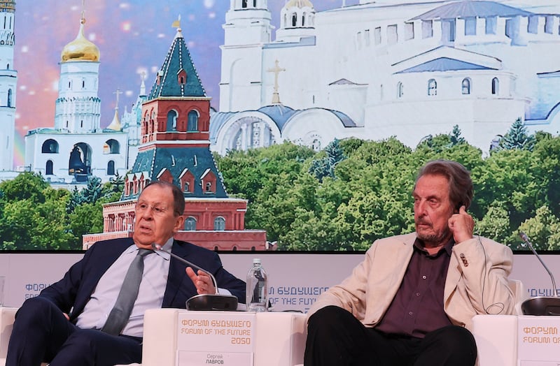 Sergey Lavrov and Errol Musk against a painted backdrop of Russian churches