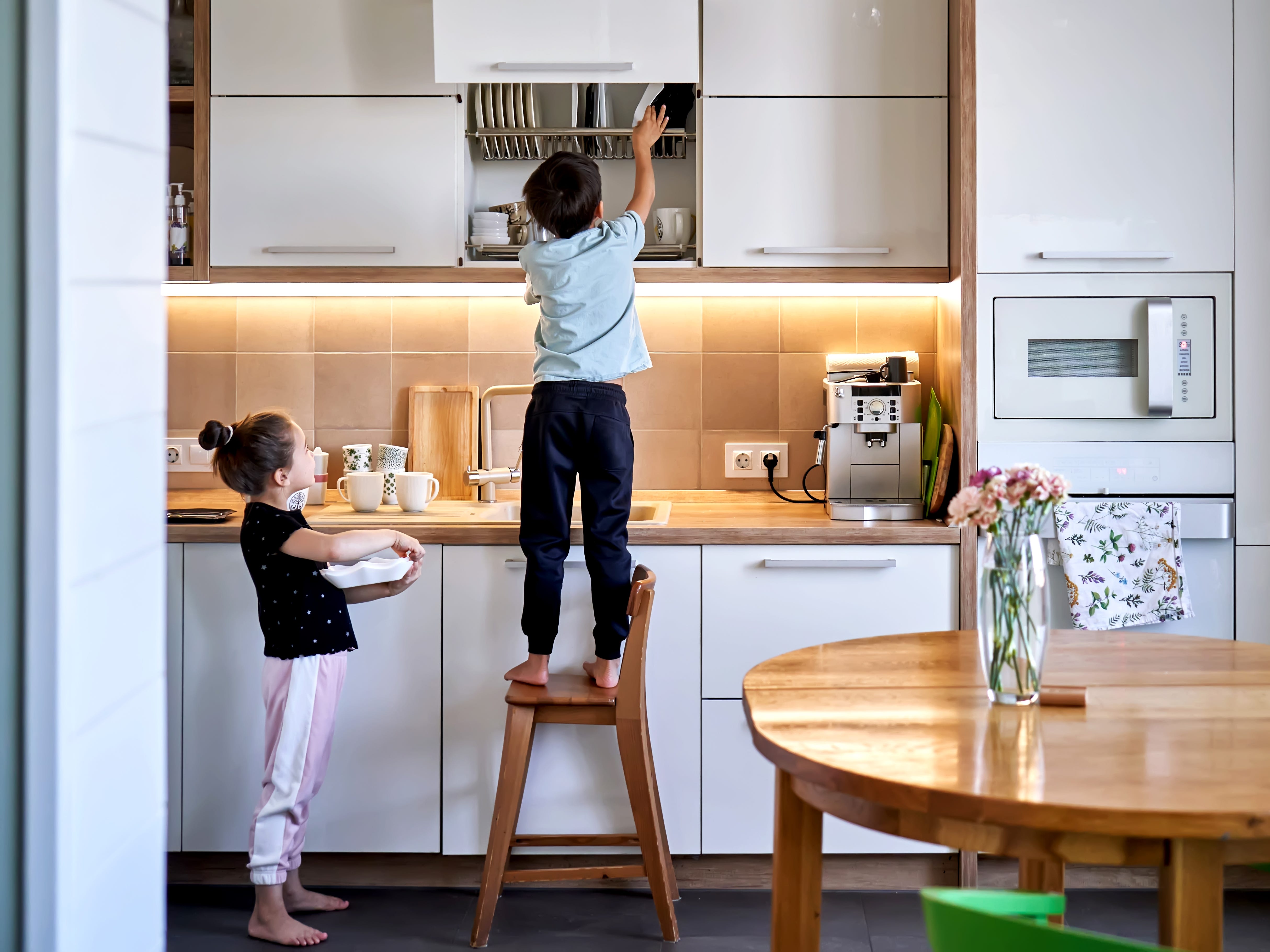 Kids helping each other put away dishes.