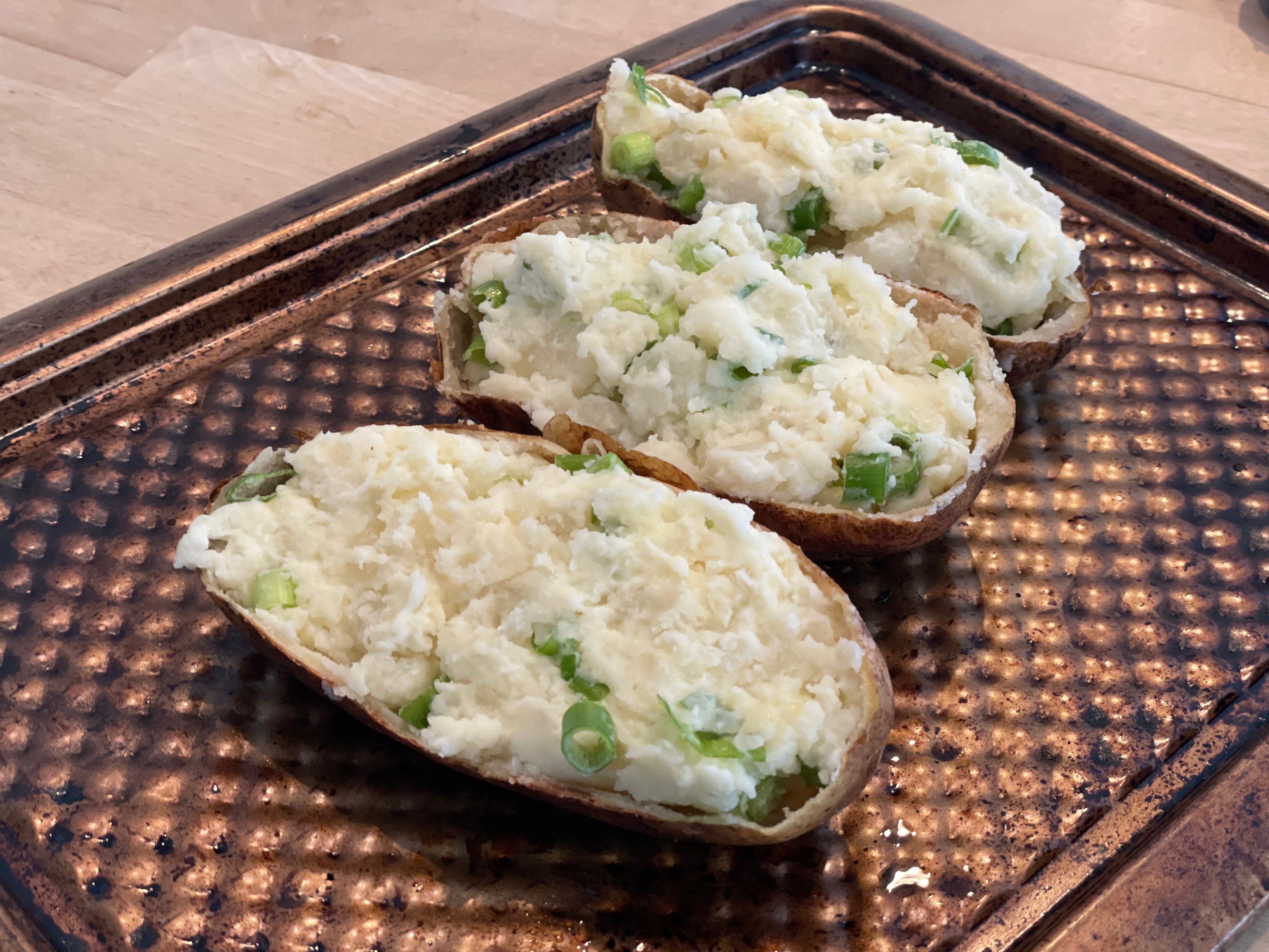 Three twice-baked potatoes on a baking sheet.