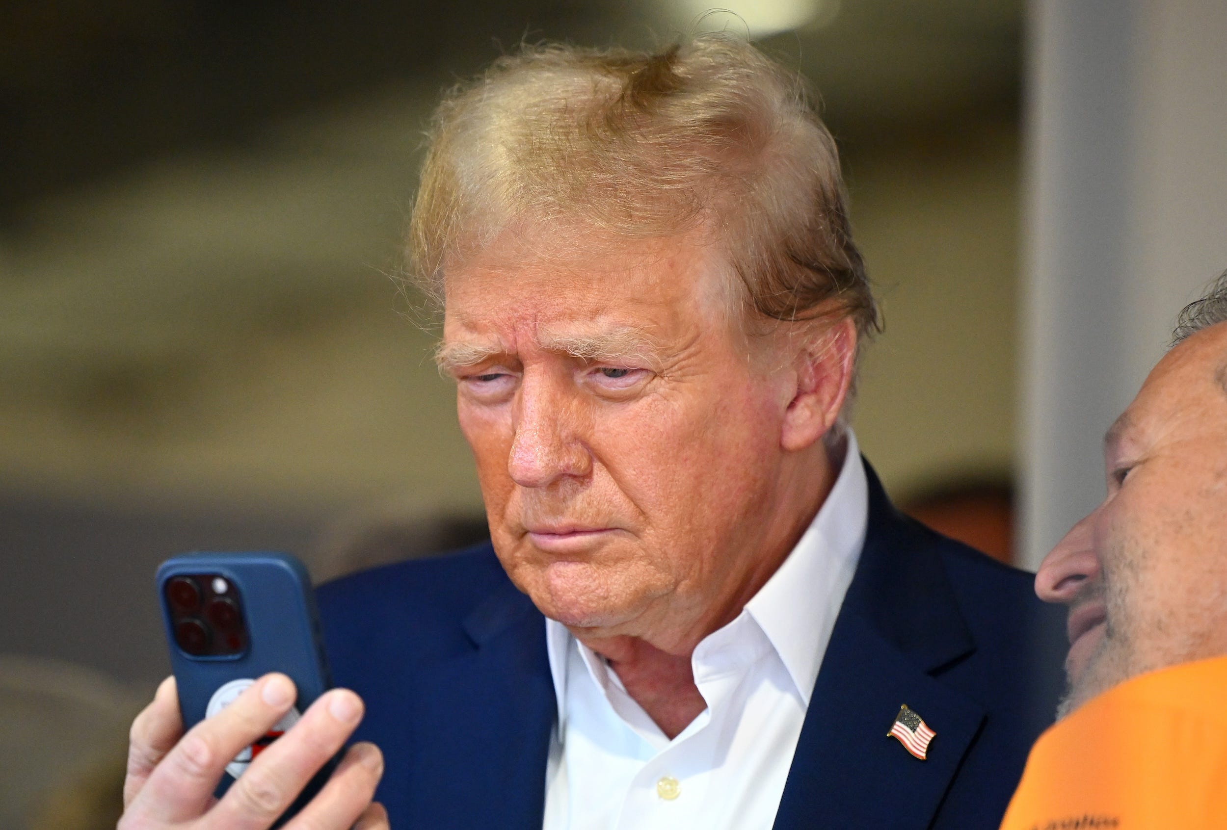 Donald Trump looks down at a phone while visiting the Miami Grand Prix