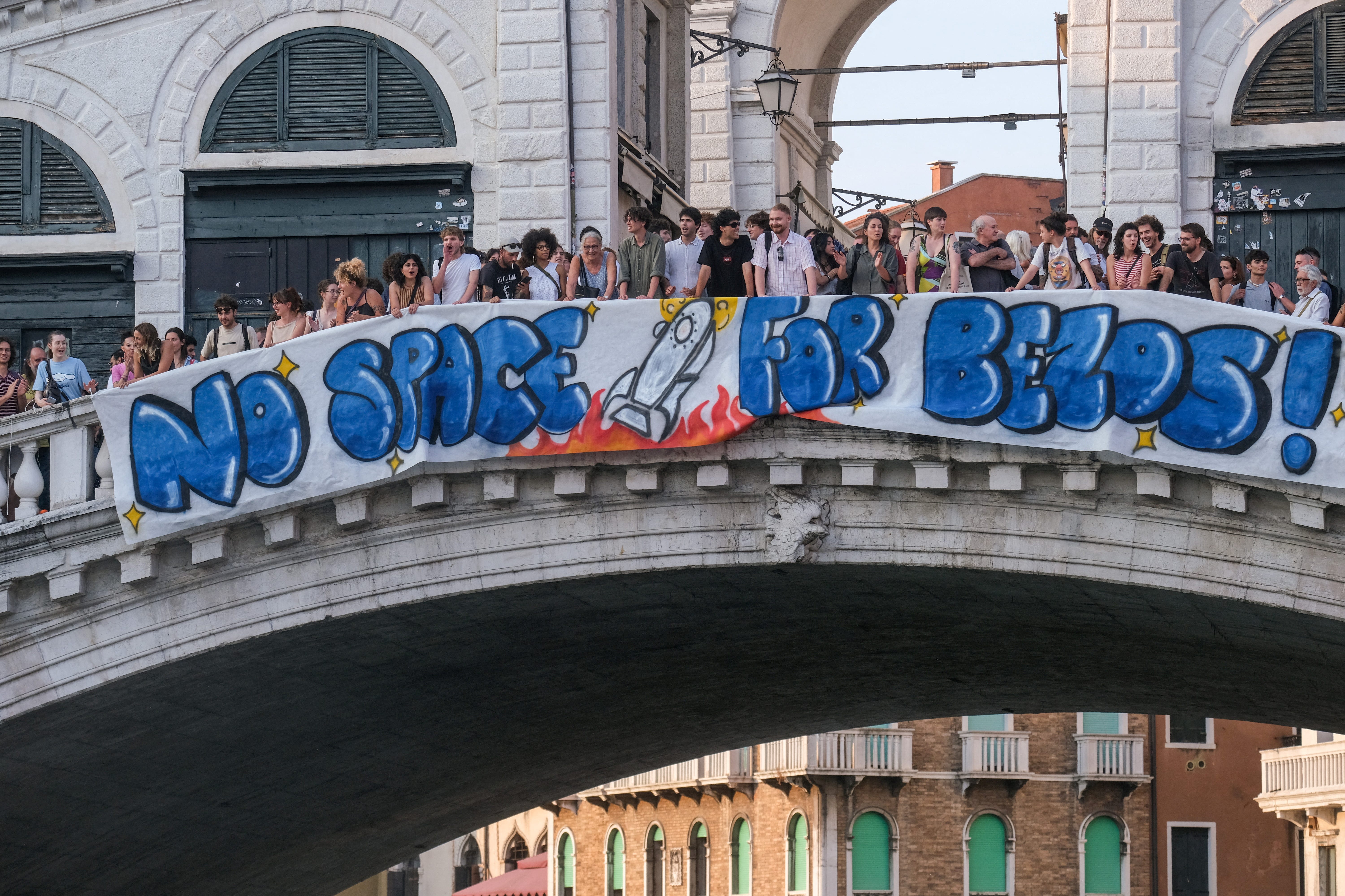 Protesters display a banner reading "No Space for Bezos!" on the Rialto Bridge