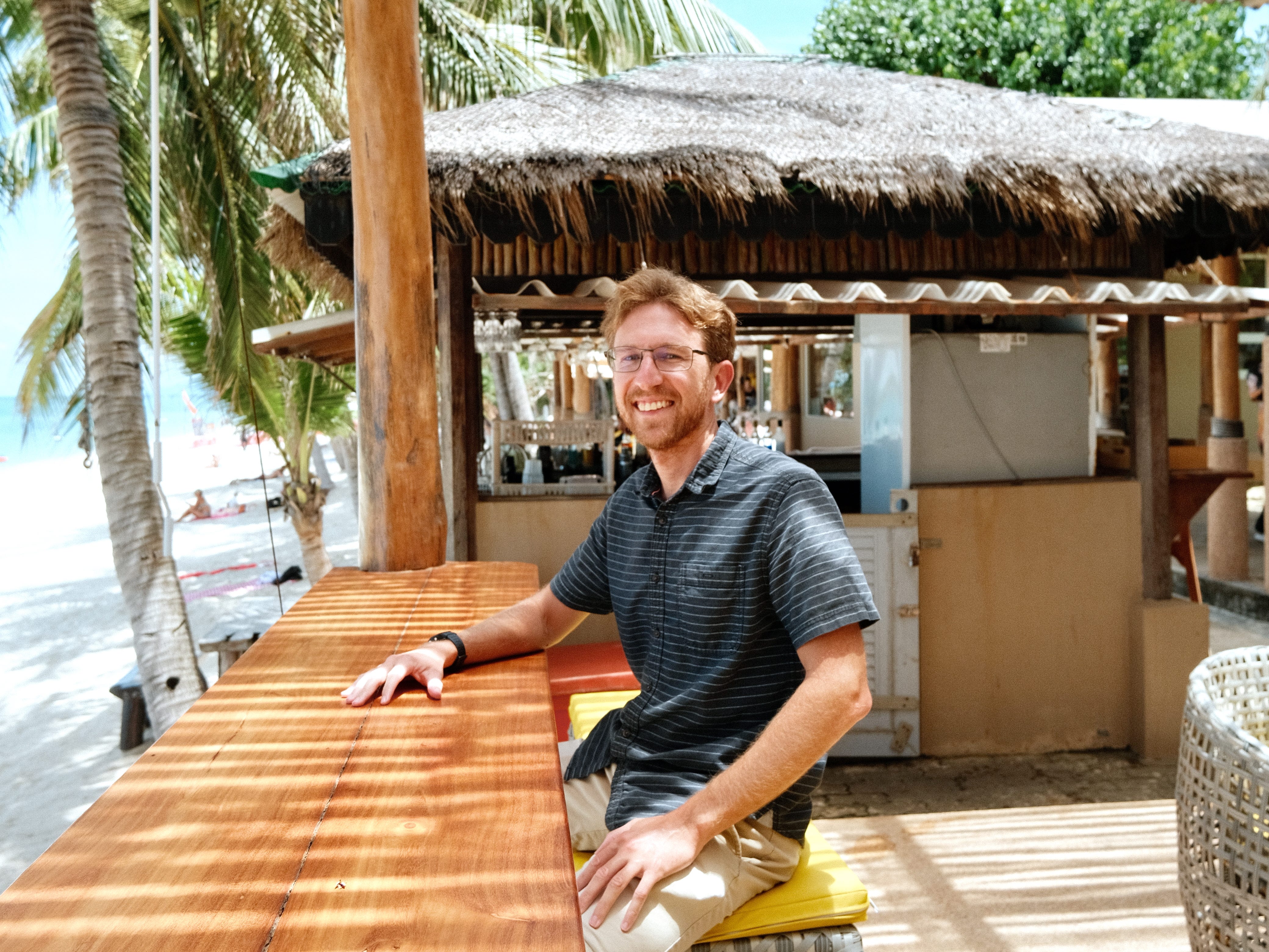 A man posing at an outdoor table in Koh Samui, Thailand.