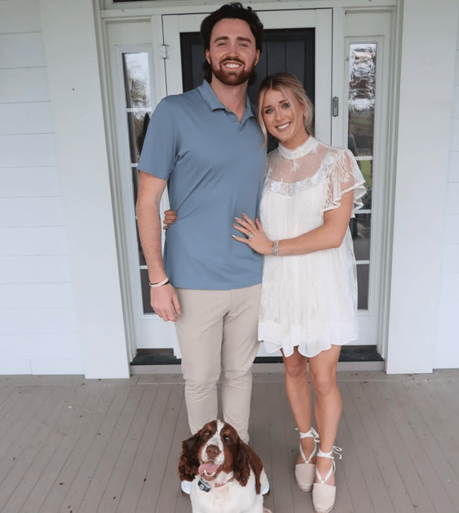 Couple posing with their dog on a porch.