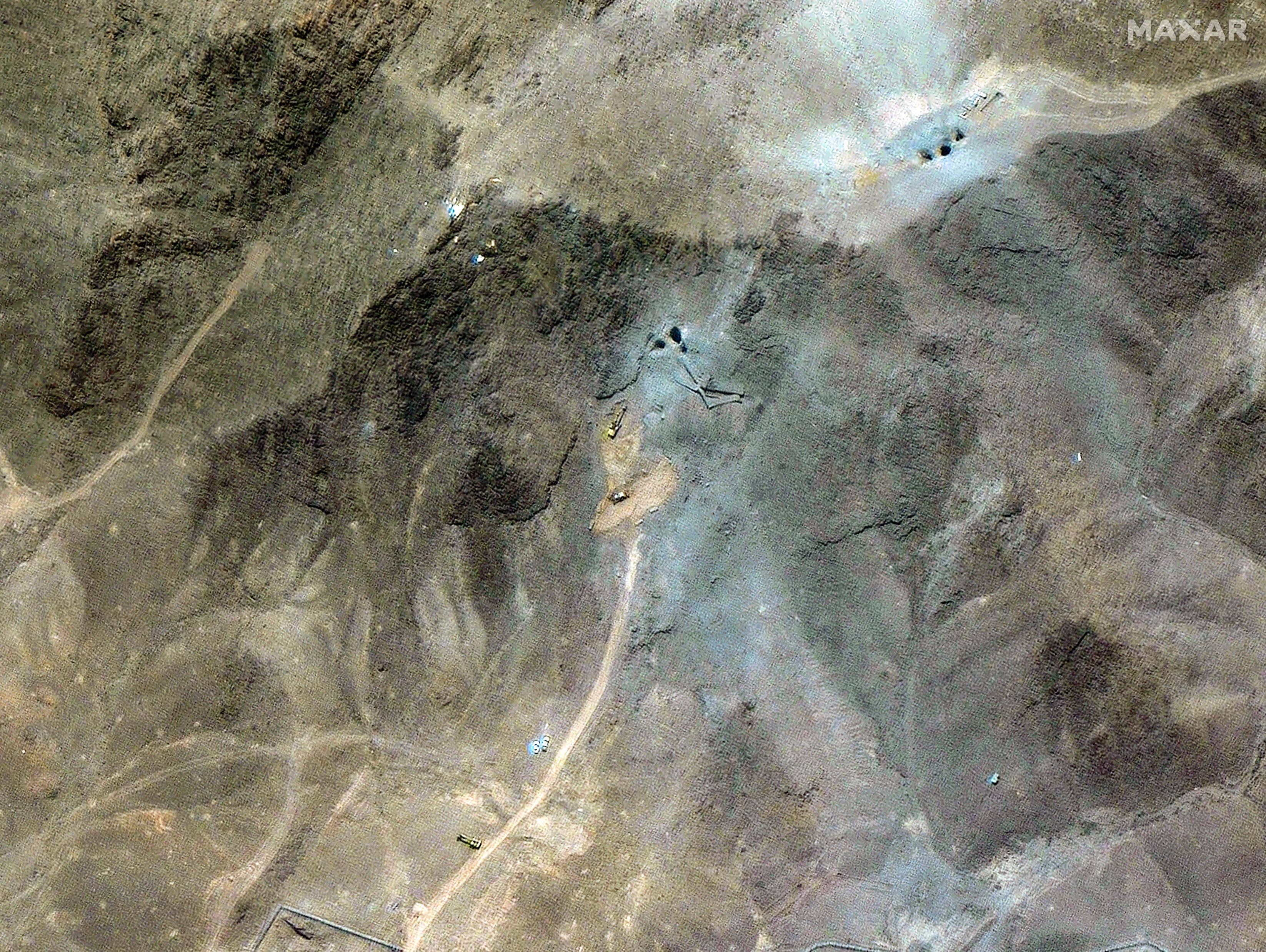 A satellite image over Iran's Fordow nuclear site in the mountains showing excavators outside the facility.