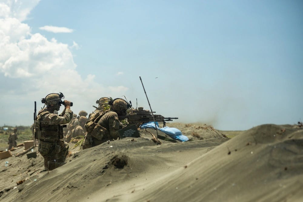 US Army soldiers fire XM-250 light machine guns and M240B medium machine guns behind sand dunes during a military exercise in the Philippines.