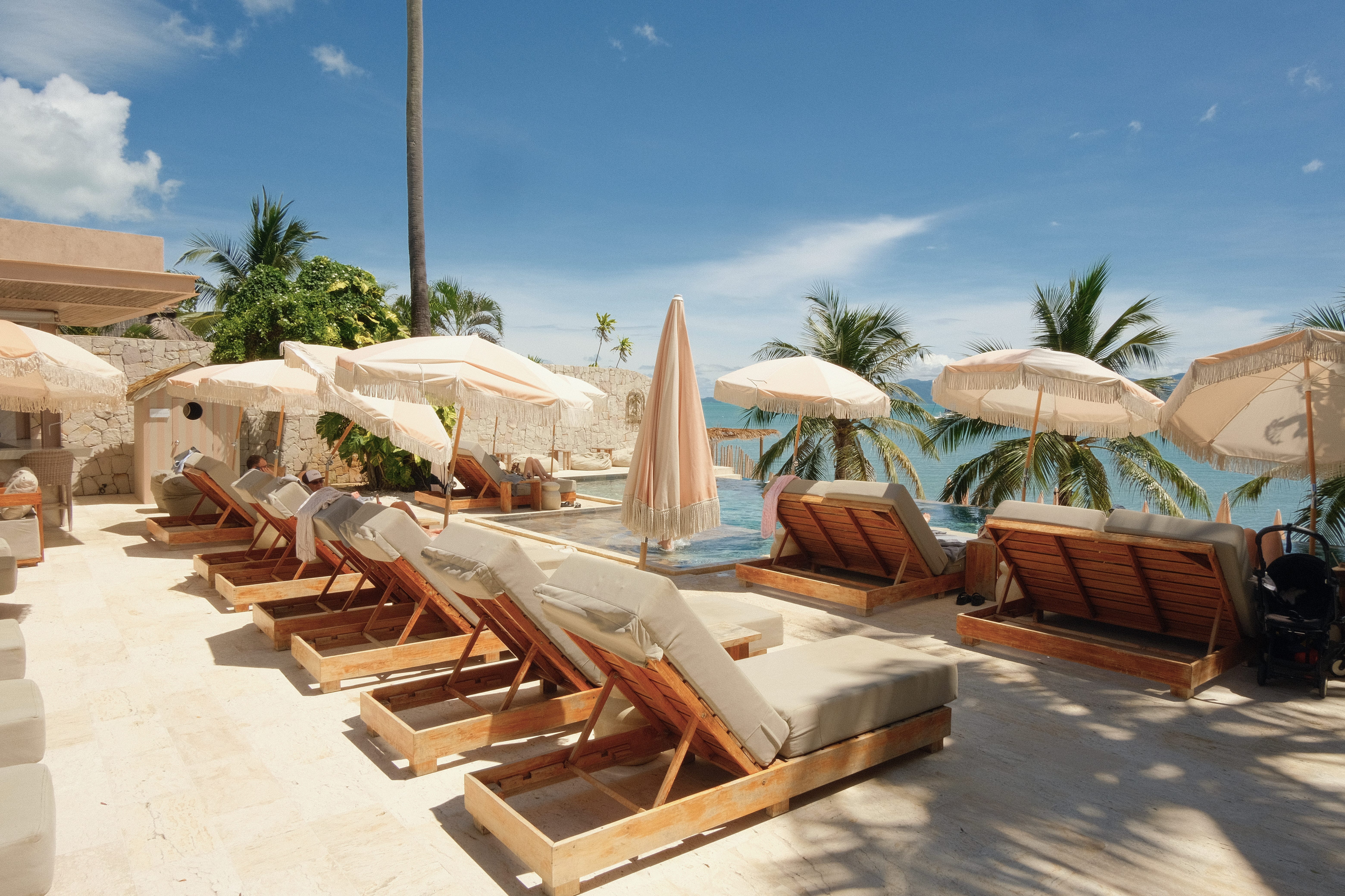 Rows of beach chairs along a pool, facing the ocean, in a boutique hotel in Koh Samui, Thailand.