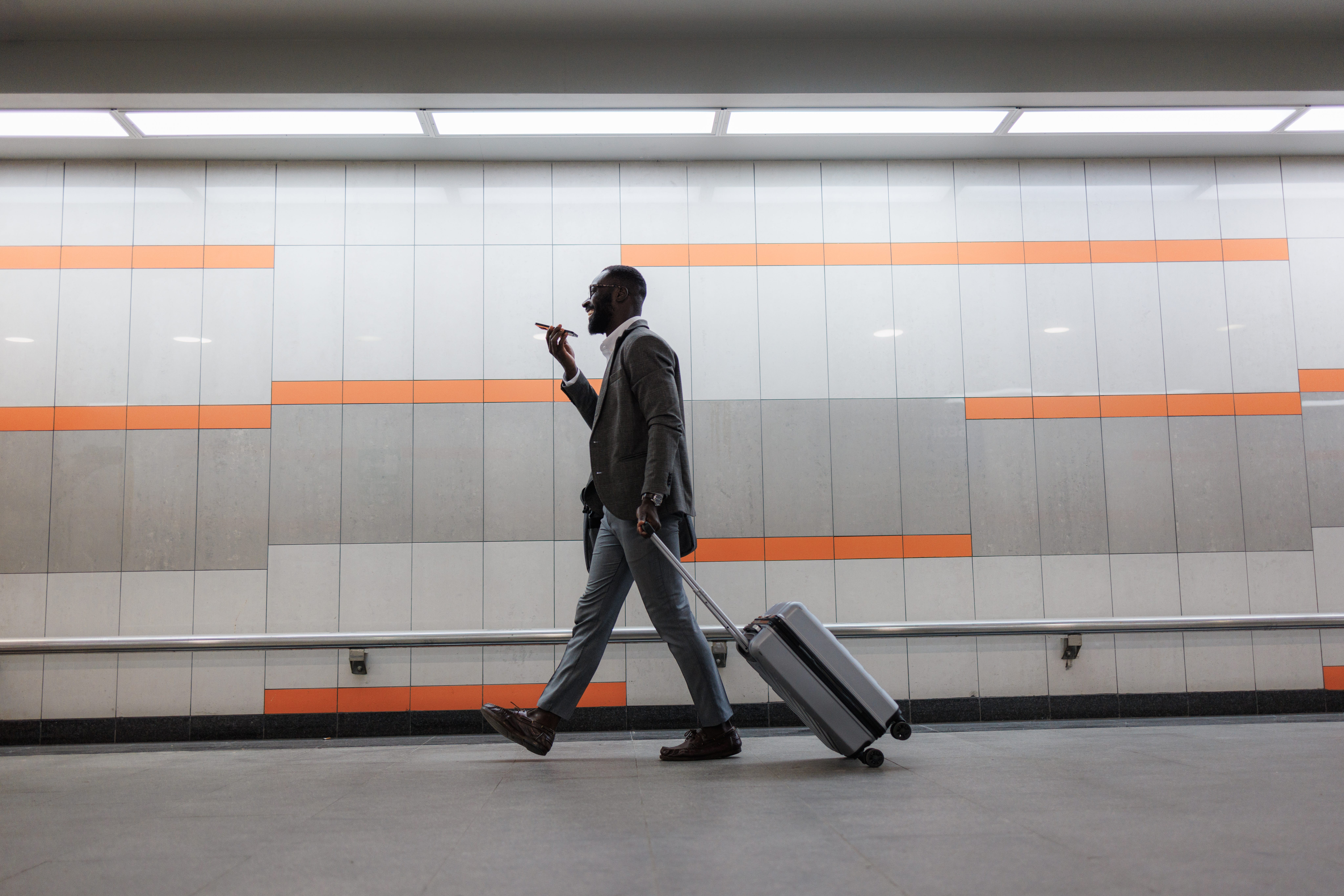 Business traveler walking with suitcase while talking on phone