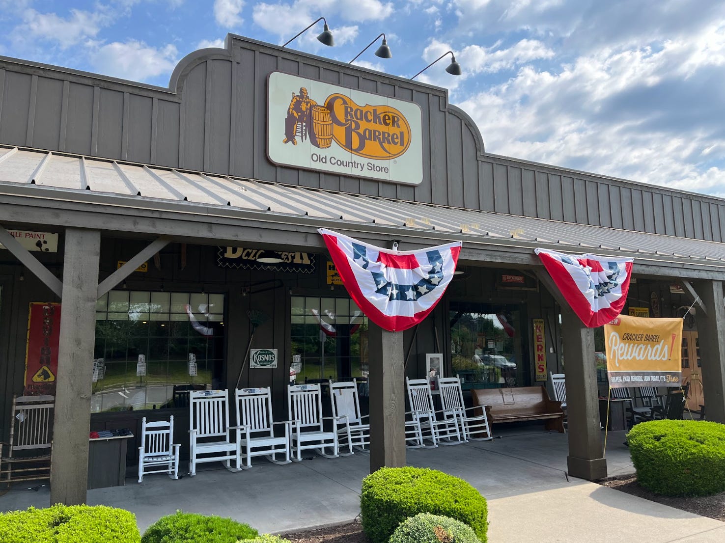 The outside of a Cracker Barrel restaurant in Northern Virginia, including an orange and brown sign and red, white, and blue banners.