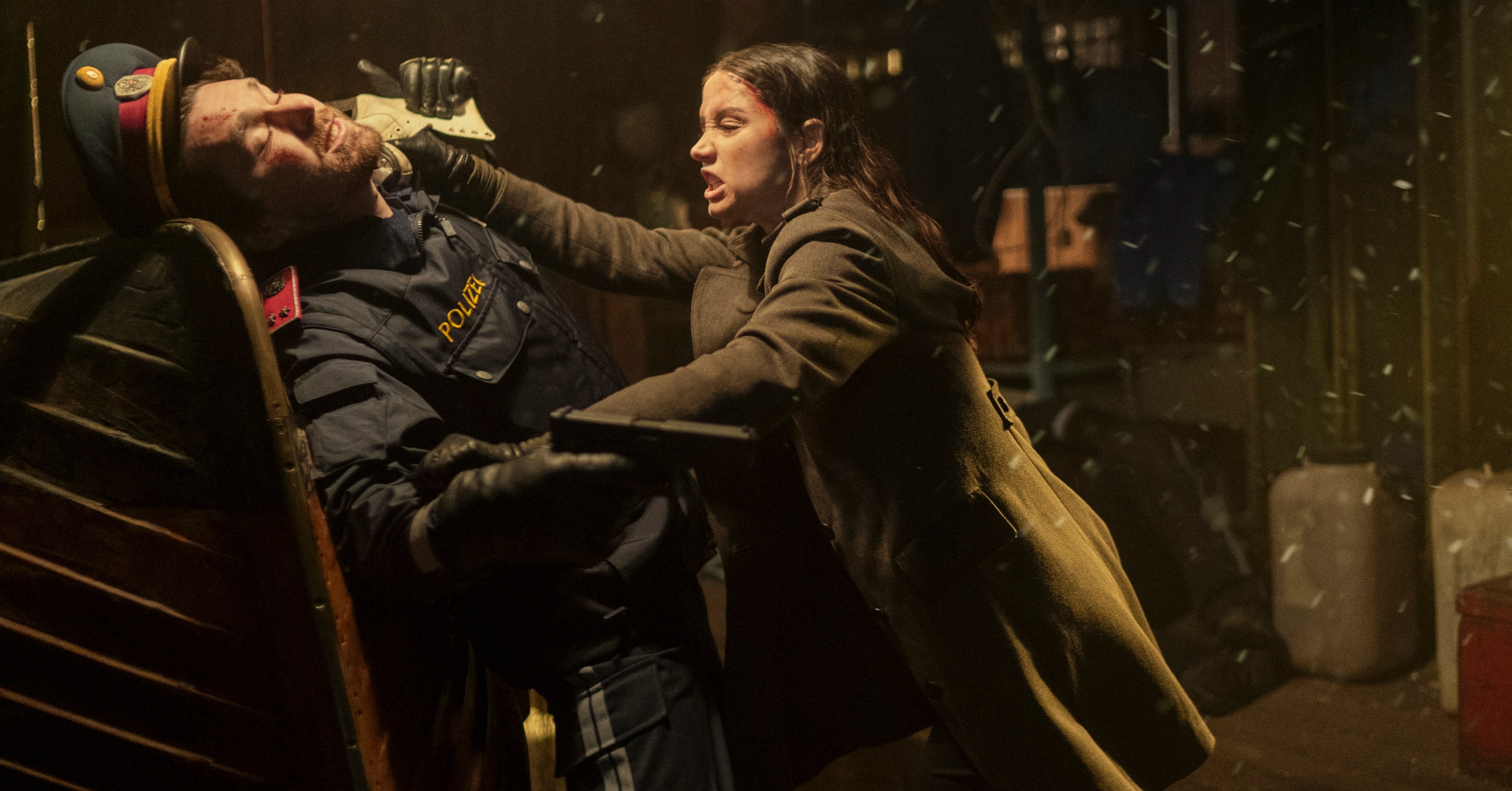 Eve (Ana de Armas) strangles a gun-wielding man in a retro military hat and trenchcoat in the John Wick spin-off Ballerina