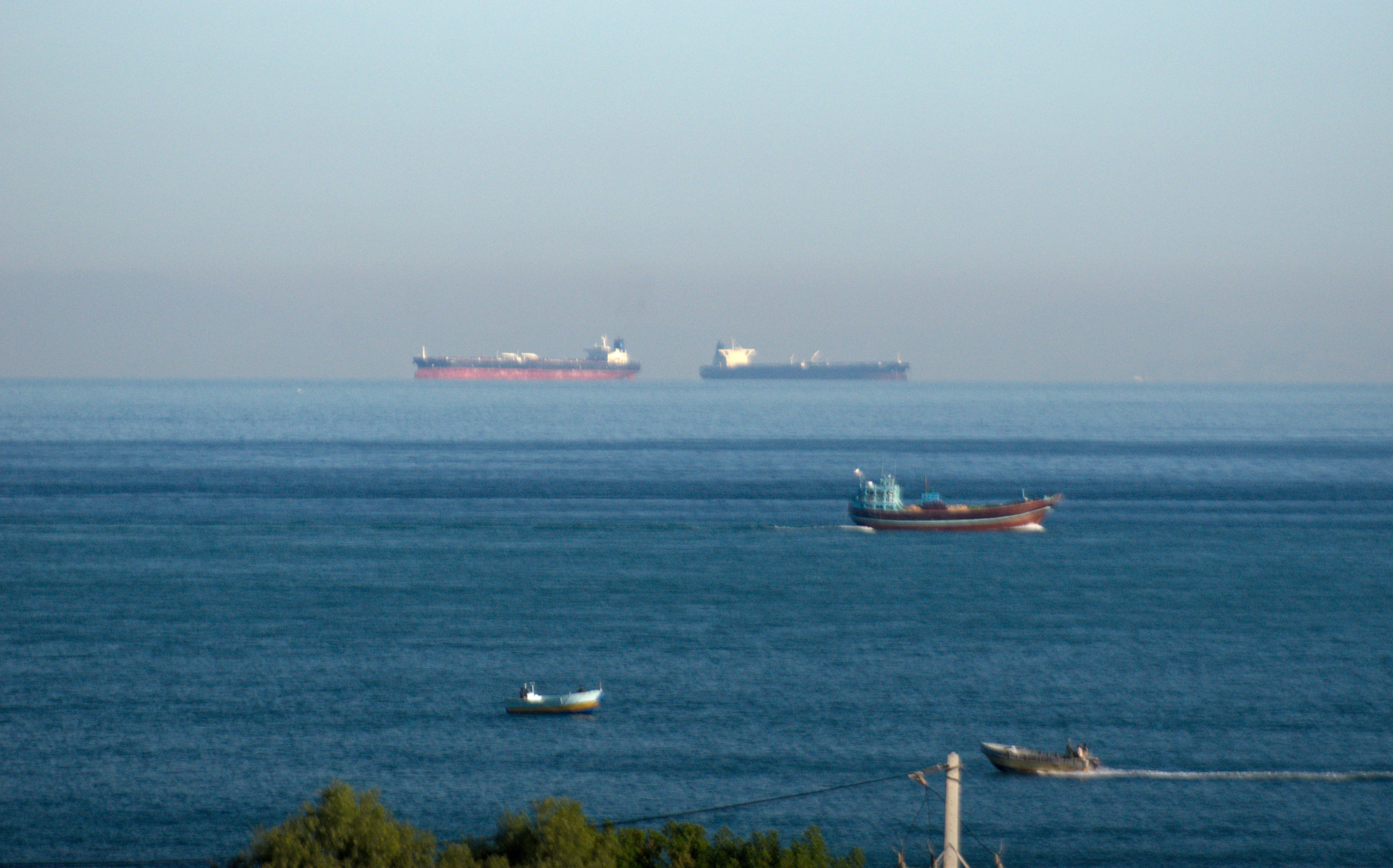 Three oil tankers on the sea, and two smaller boats.