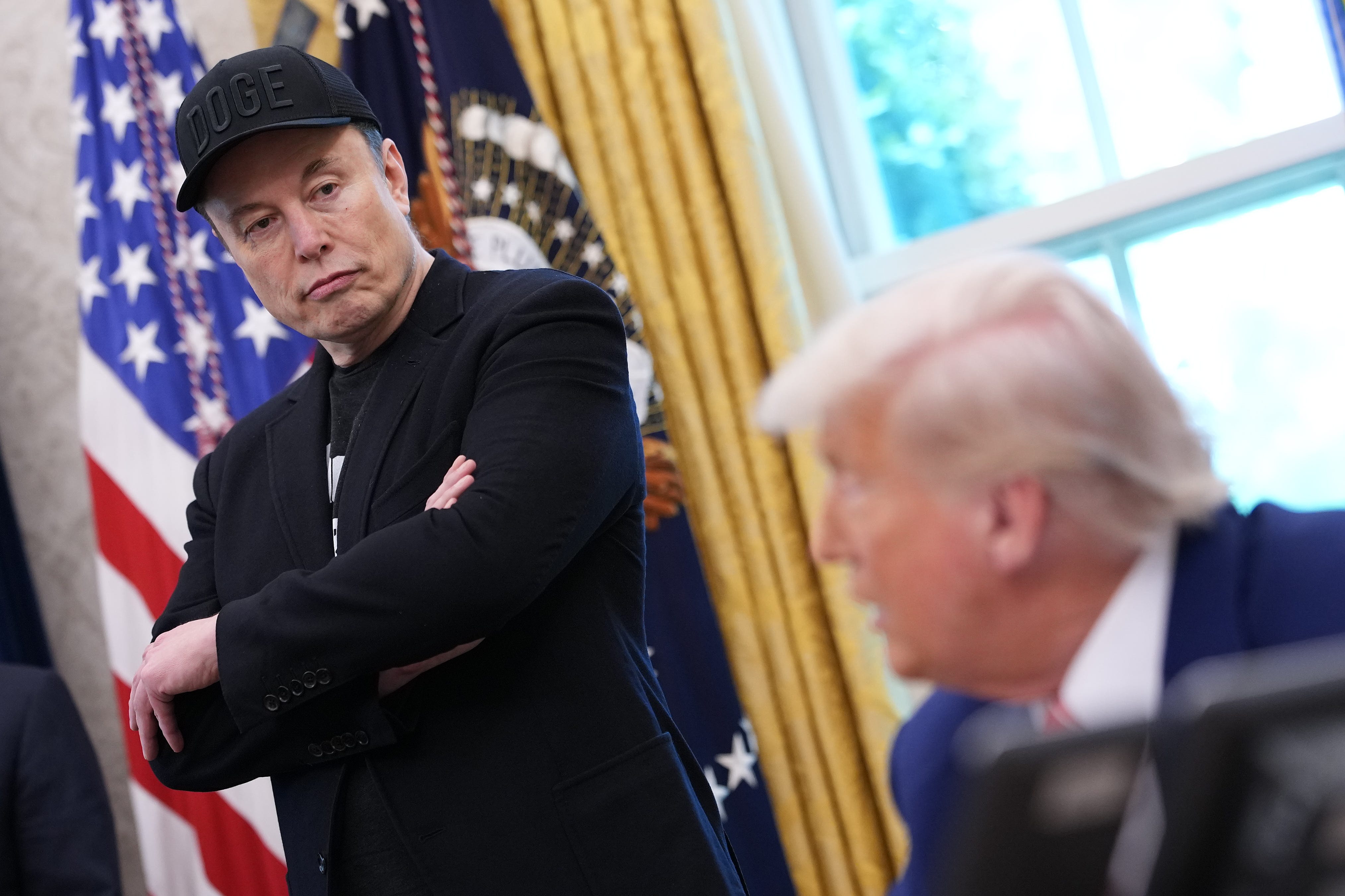 Elon Musk looking at President Donald Trump in the Oval Office at the White House.