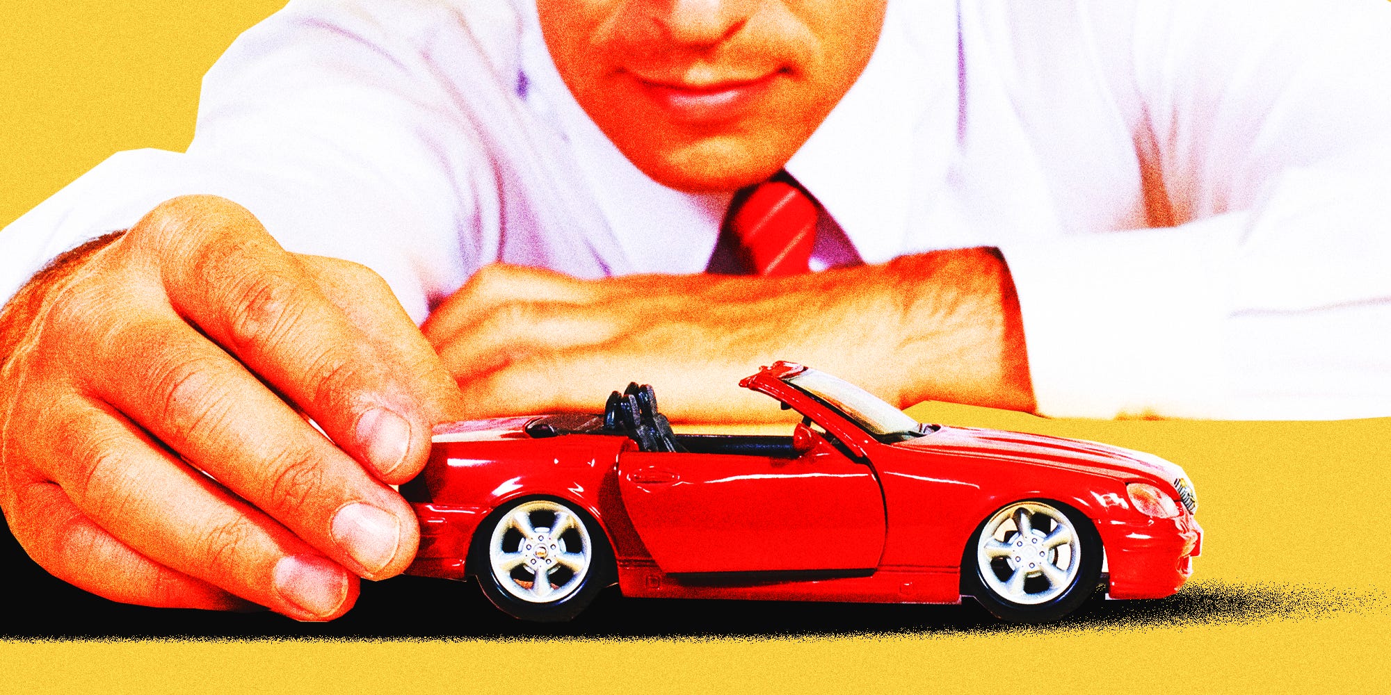 A businessman playing with a toy sports car