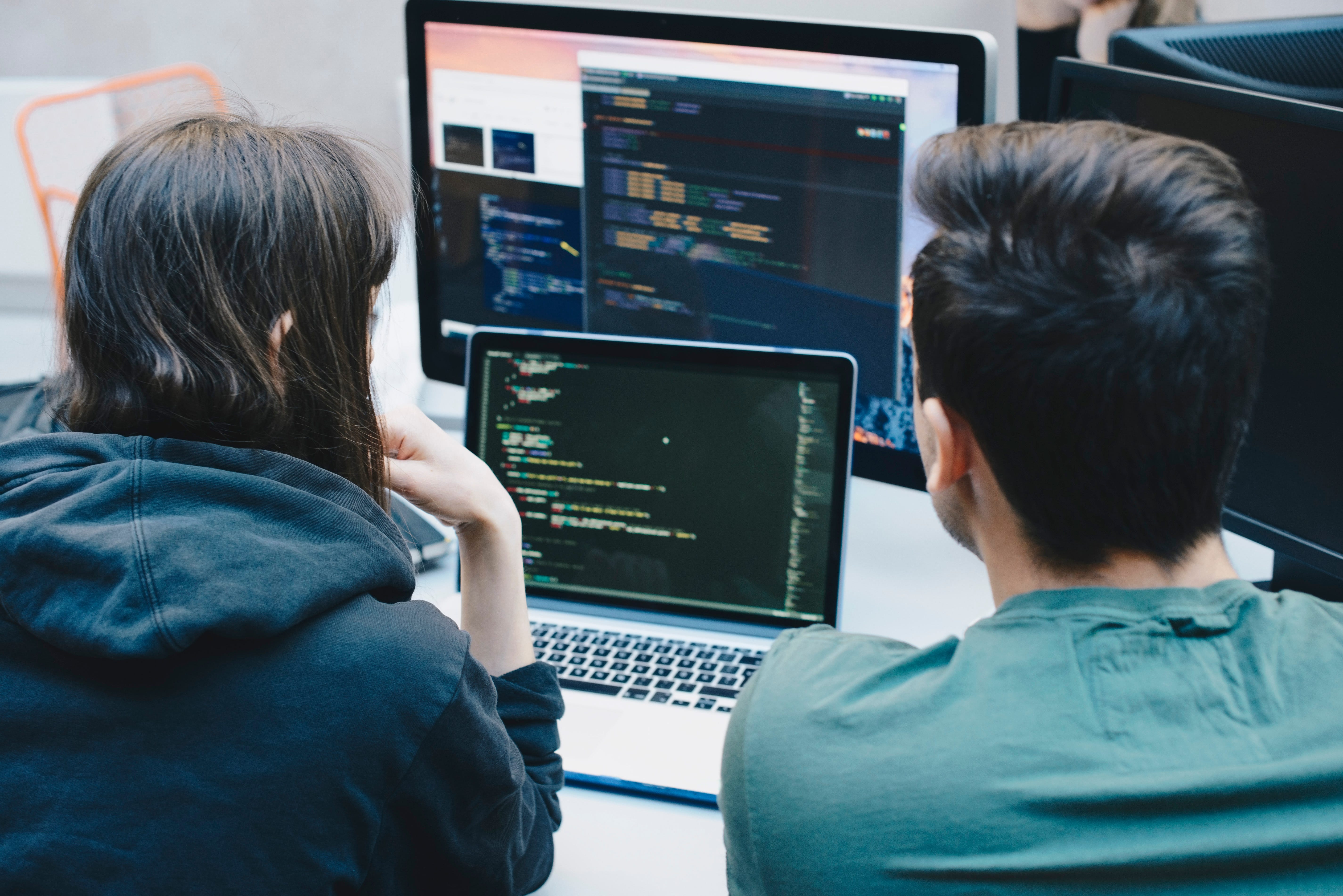 Two people working on a computer coding