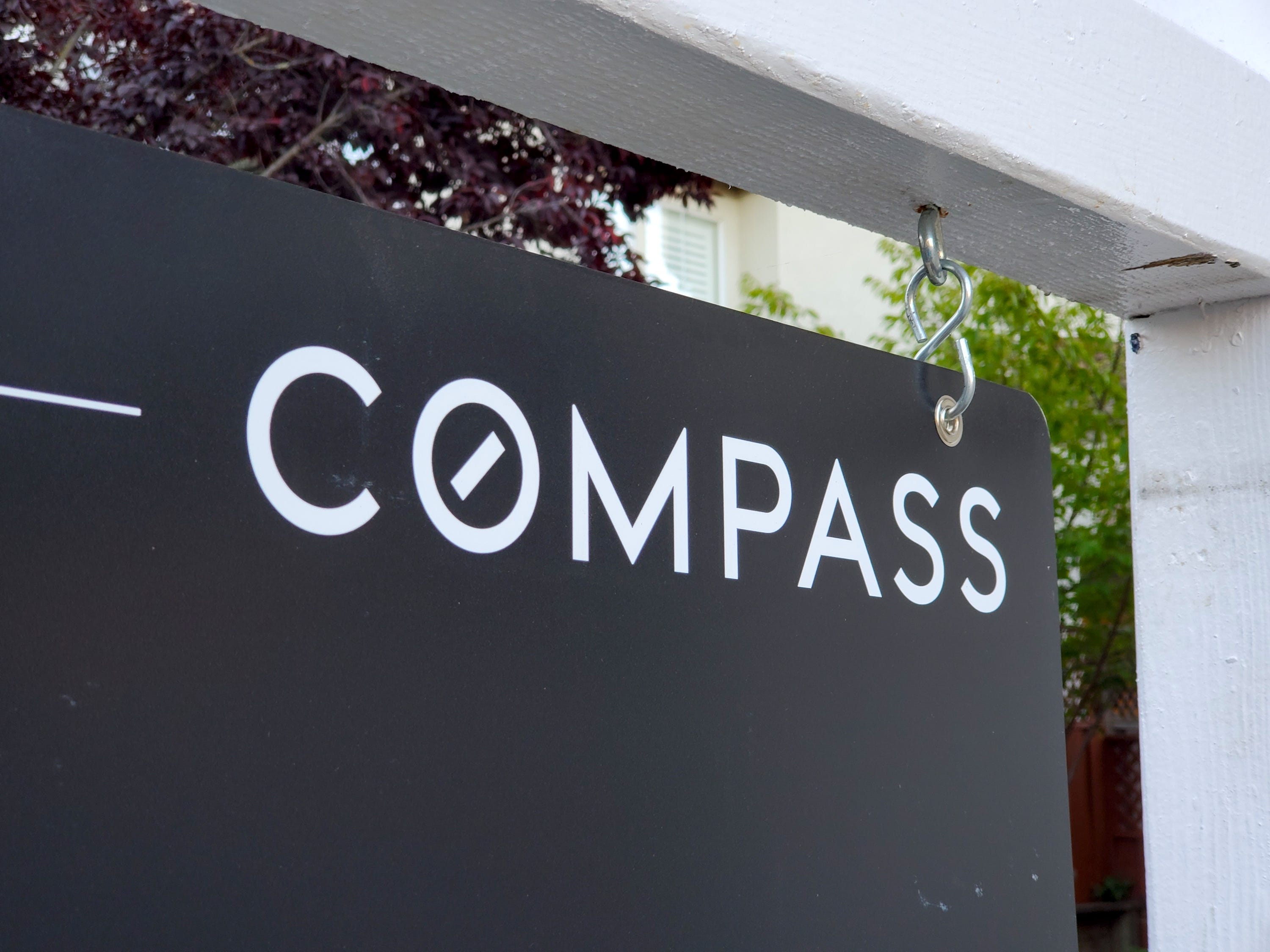 A Compass Realty for-sale sign in front of a house