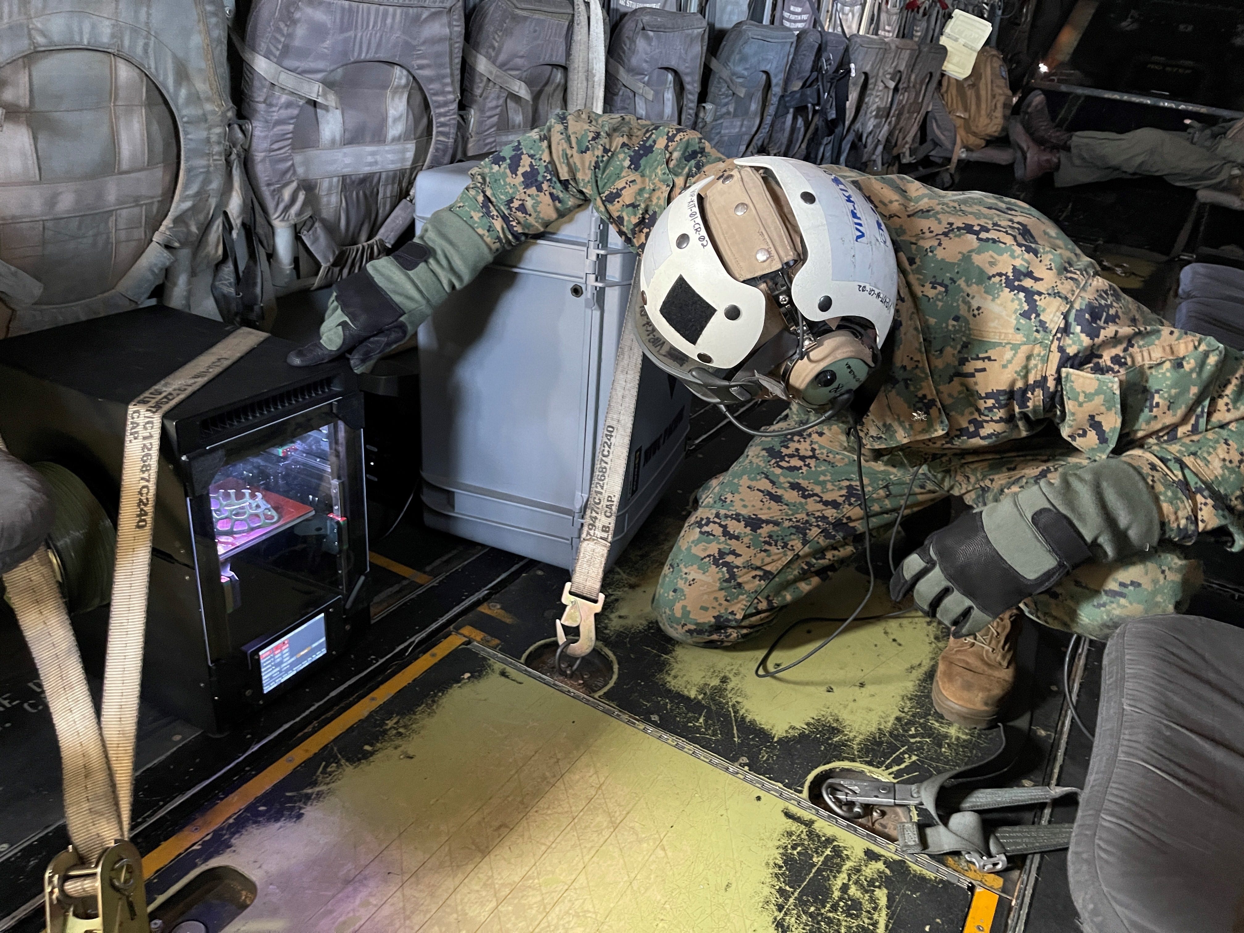 US Marine Corps Lt. Col. Michael Radigan checks on the 3D printing of a medical cast aboard an MV-22 Osprey during a training flight near Twentynine Palms, Calif. on June 21 2023.