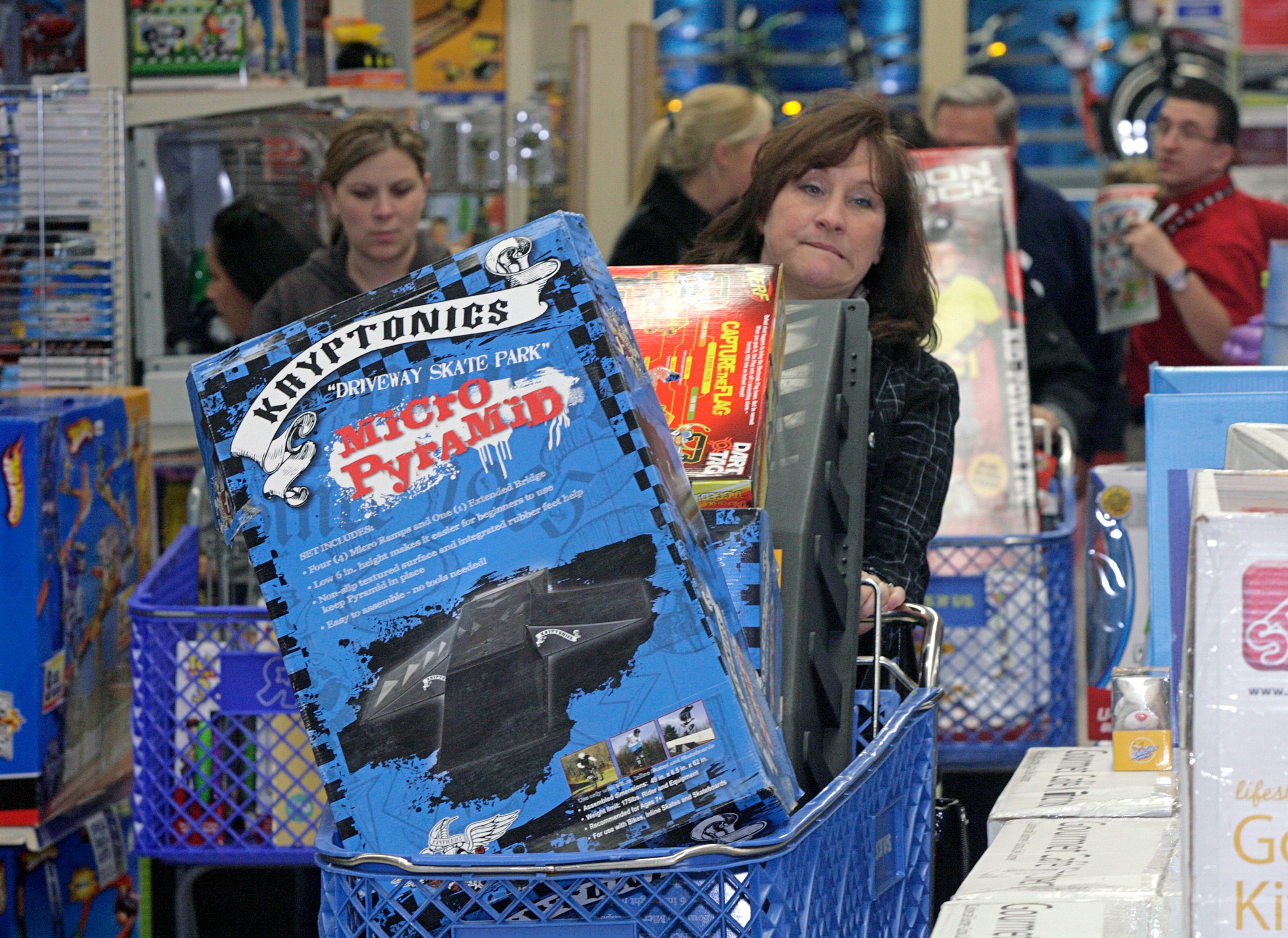 A woman in a full cart with a toy aisle.