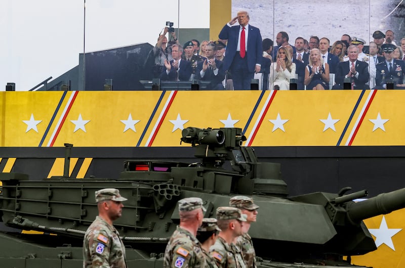 President Donald Trump, next to Secretary of Defense Pete Hegseth and first lady Melania Trump, salutes troops during his long-sought military parade.