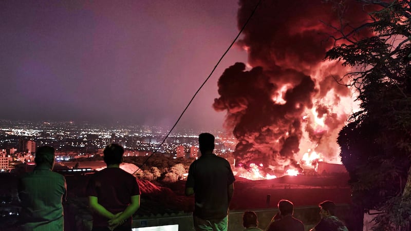 People observe fire and smoke from an Israeli attack on the Shahran oil depot on June 15 in Tehran. Iran's foreign minister said the country would respond