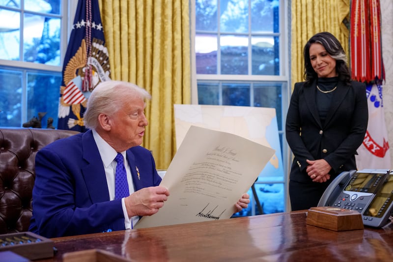 WASHINGTON, DC - FEBRUARY 12: U.S. President Donald Trump signs Tulsi Gabbard's commission for her new role as Director of National Intelligence after she was sworn in, in the Oval Office at the White House on February 12, 2025 in Washington, DC. Gabbard, who will oversee the 18 intelligence agencies and serve as Trump's advisory on intelligence, was confirmed by the Senate 52-48. (Photo by Andrew Harnik/Getty Images)