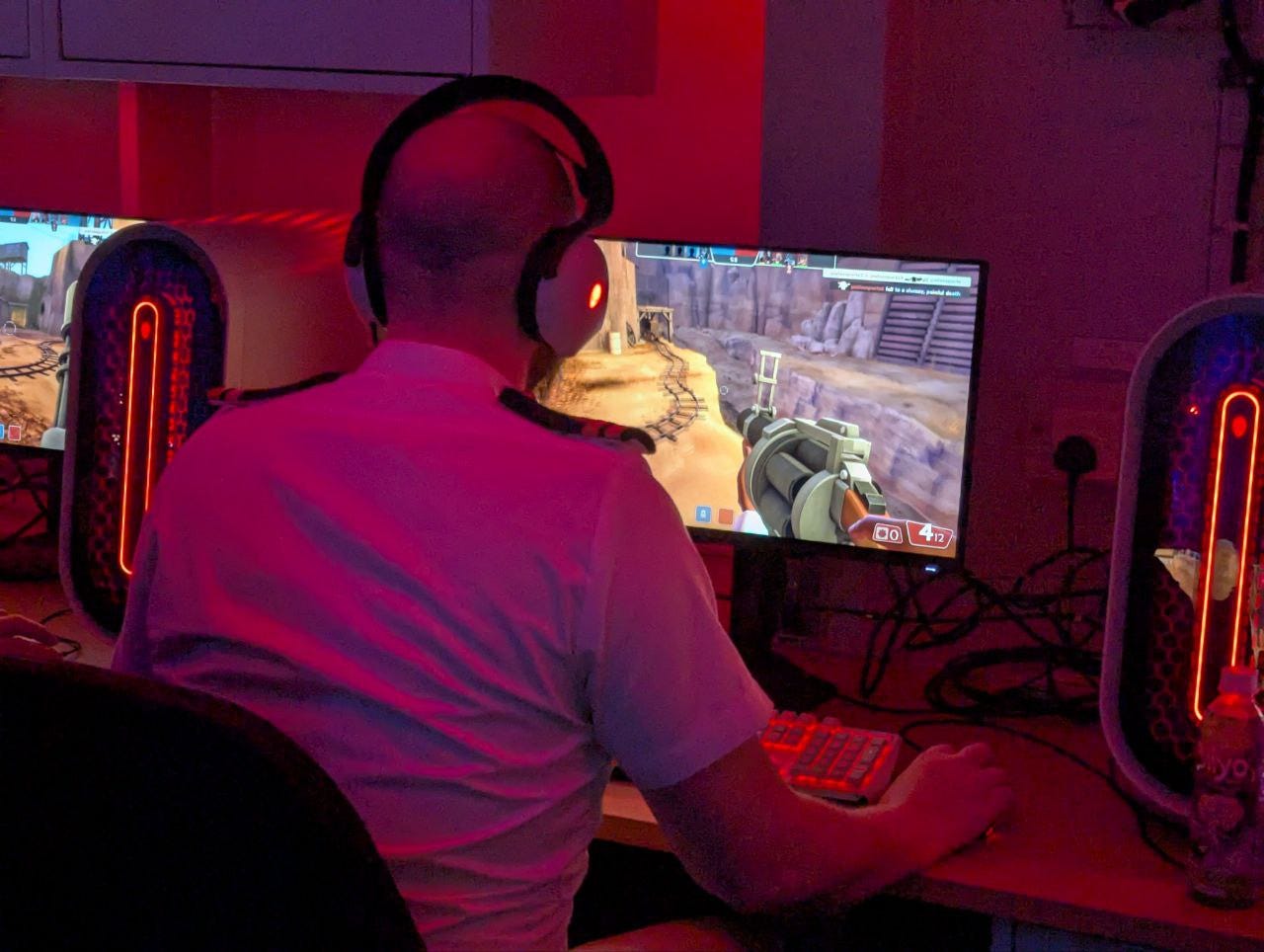 A uniformed Royal Navy lieutenant faces away and plays a video game.