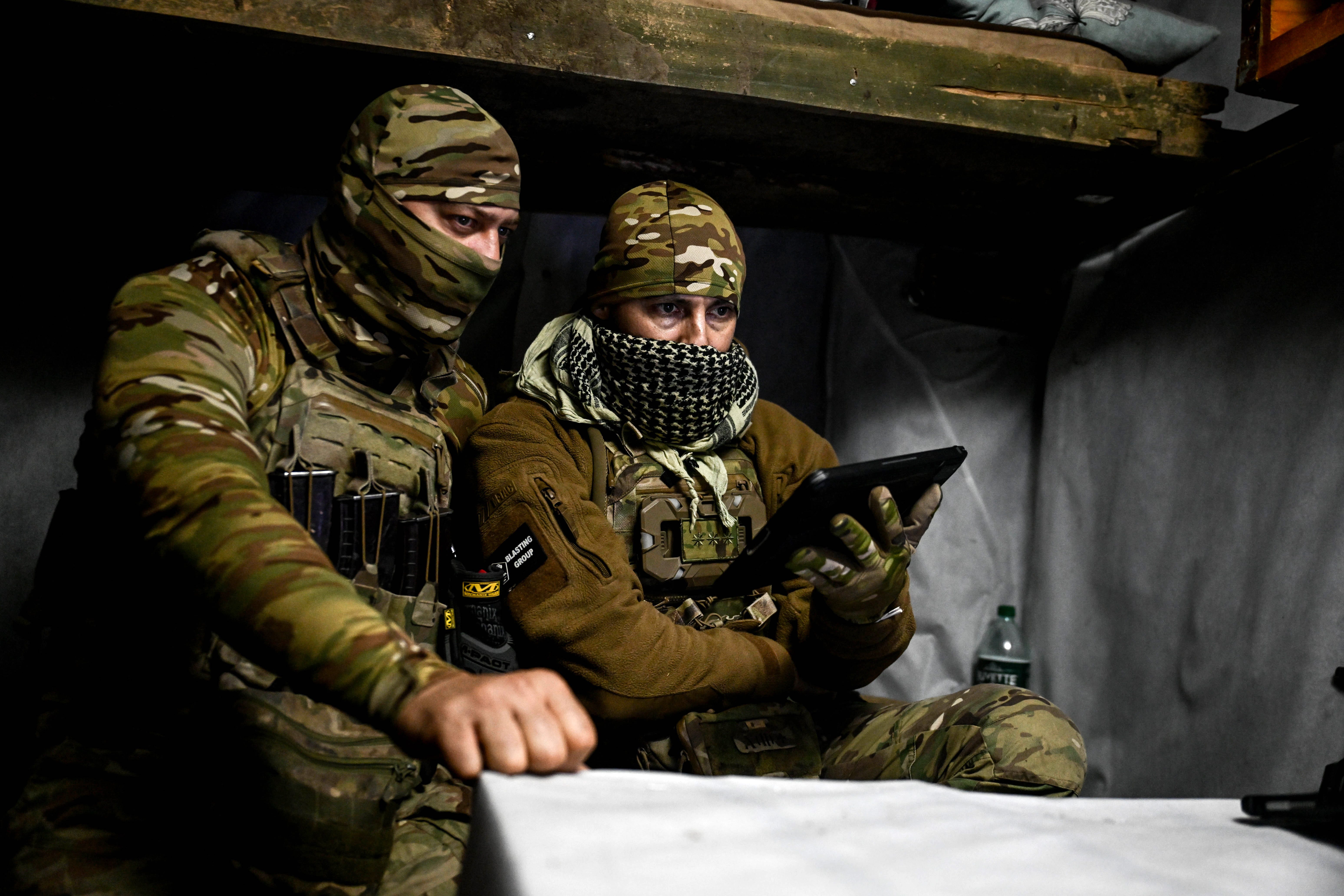 Fighters of the UAV unit of the Striletskyi Special Police Battalion look at a screen from a dugout in Zaporizhzhia.