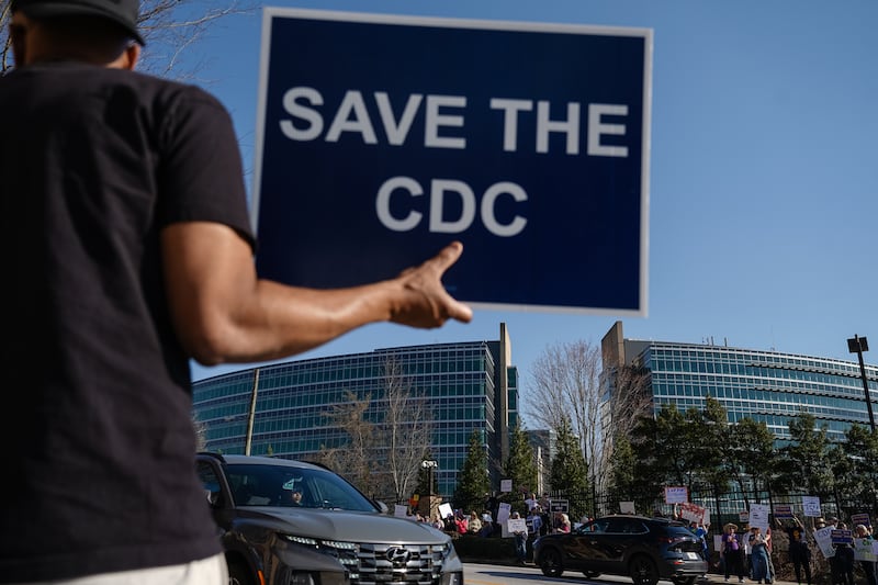 ATLANTA, GEORGIA - MARCH 12: People protesting personnel cuts at the Centers for Disease Control (CDC) hold signs outside the organization's main headquarters on March 12, 2025 in Atlanta, Georgia. Some Centers for Disease Control and Prevention (CDC) employees have sent a letter to CDC leadership, they argue their dismissals were unfair and violated due process as they face a deadline that could officially end their employment status. (Photo by Elijah Nouvelage/Getty Images)