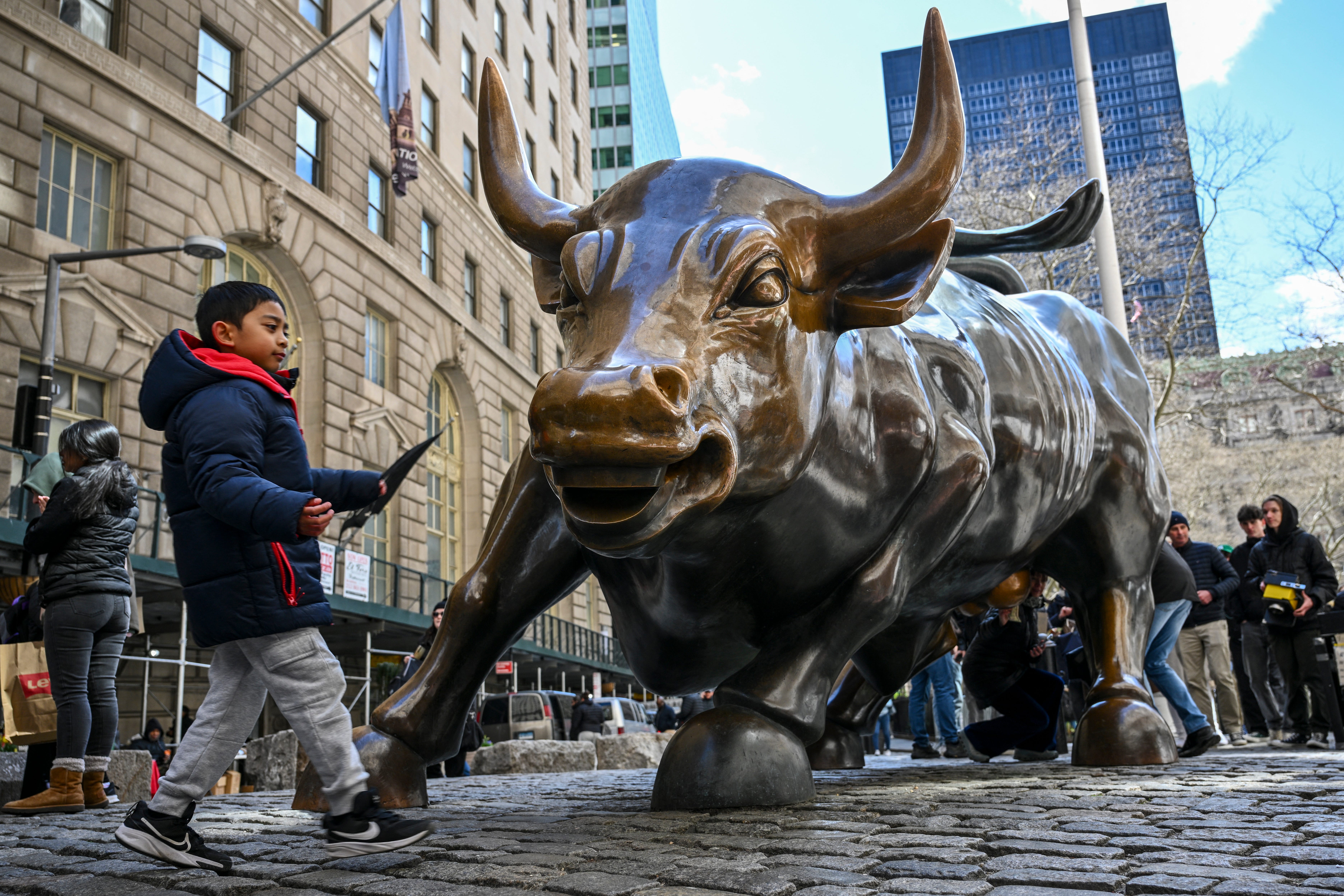 A boy walks by the famous Wall Street bull statue