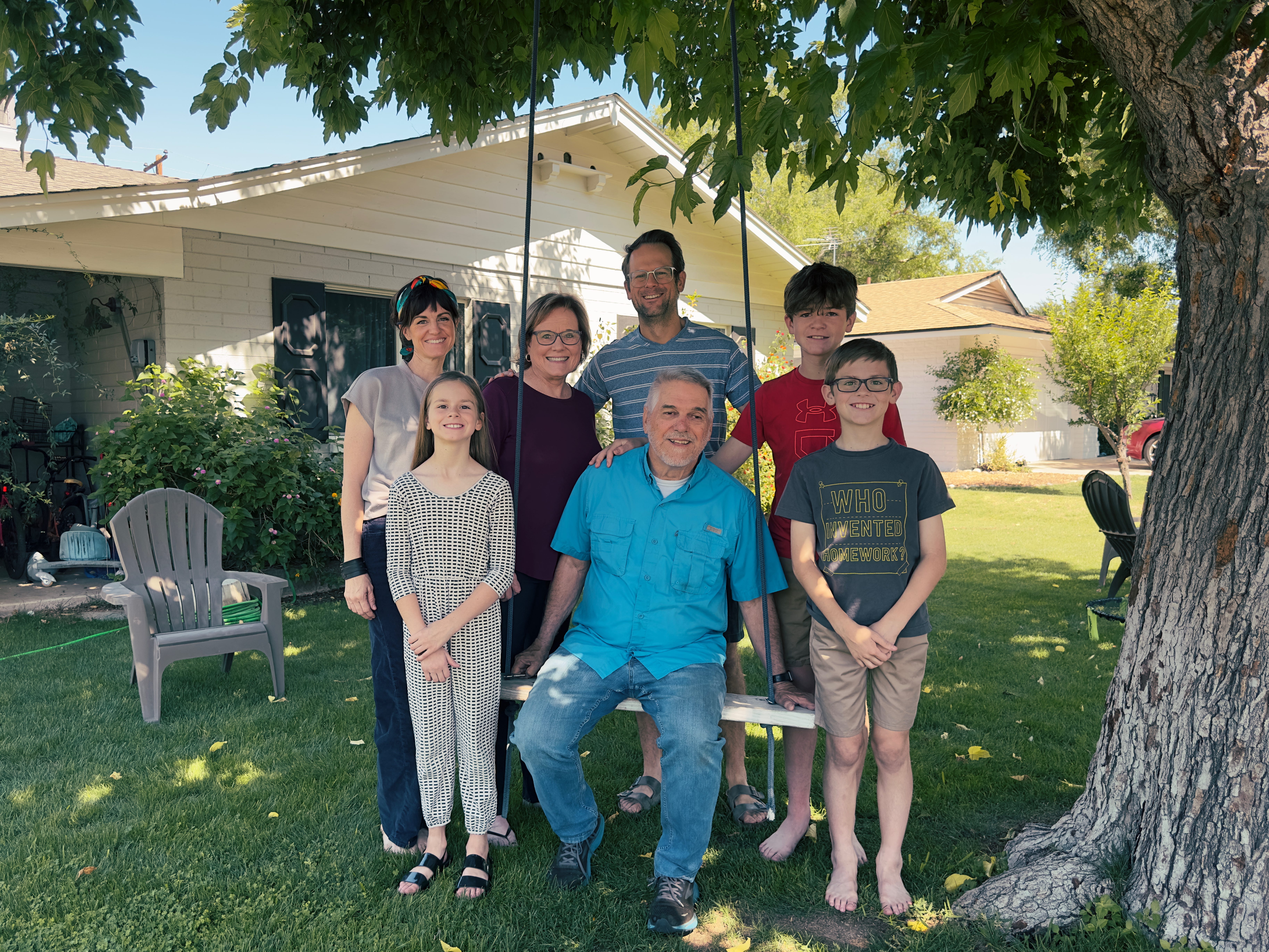 The author and her family of five with her two parents by a tree with a swing in the yard of their house.