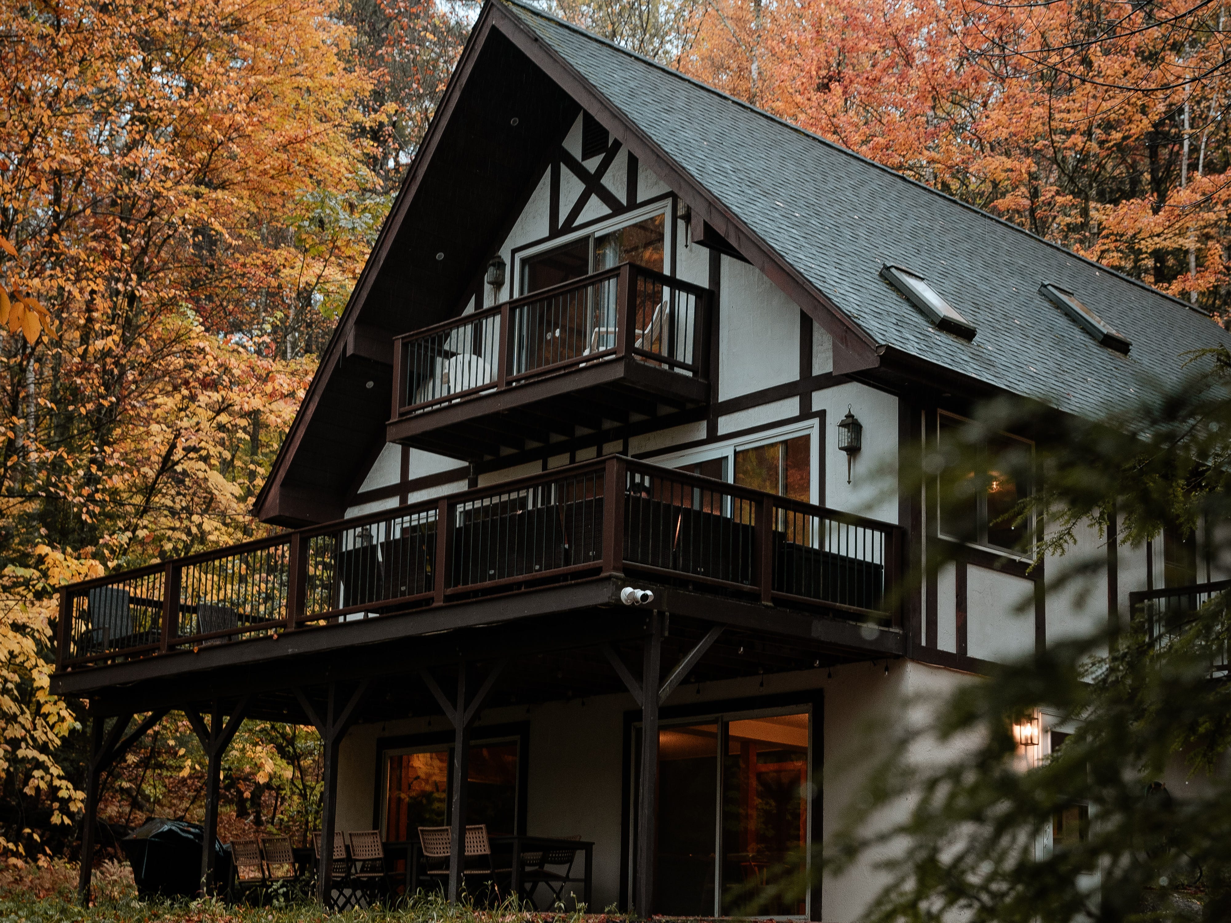Home with balcony in front of trees with yellow and orange leaves