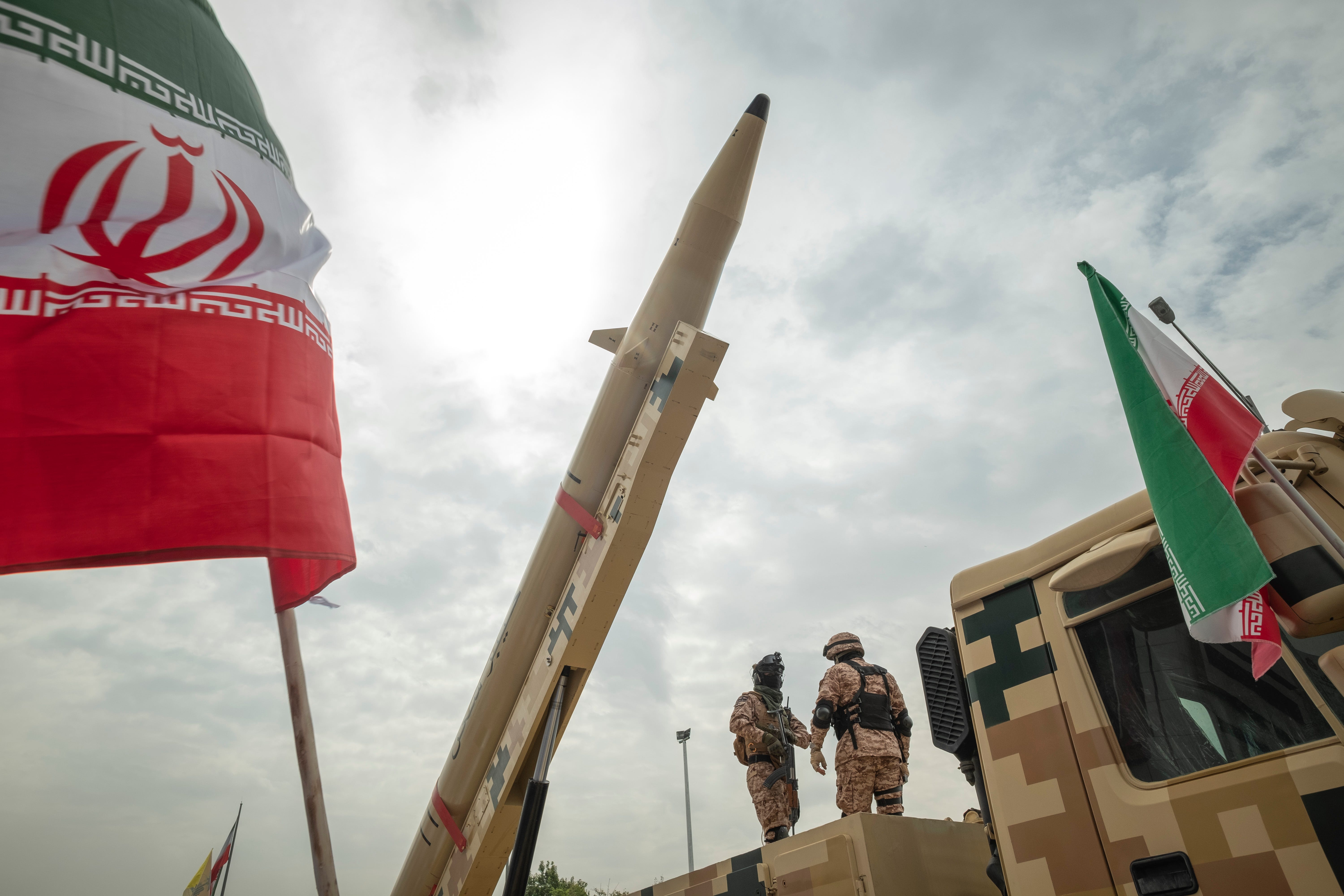 Two Islamic Revolutionary Guard Corps military personnel stand guard under an Iranian Kheibar Shekan Ballistic missile in downtown Tehran during a rally commemorating the International Quds Day, also known as the Jerusalem day, on April 29, 2022.
