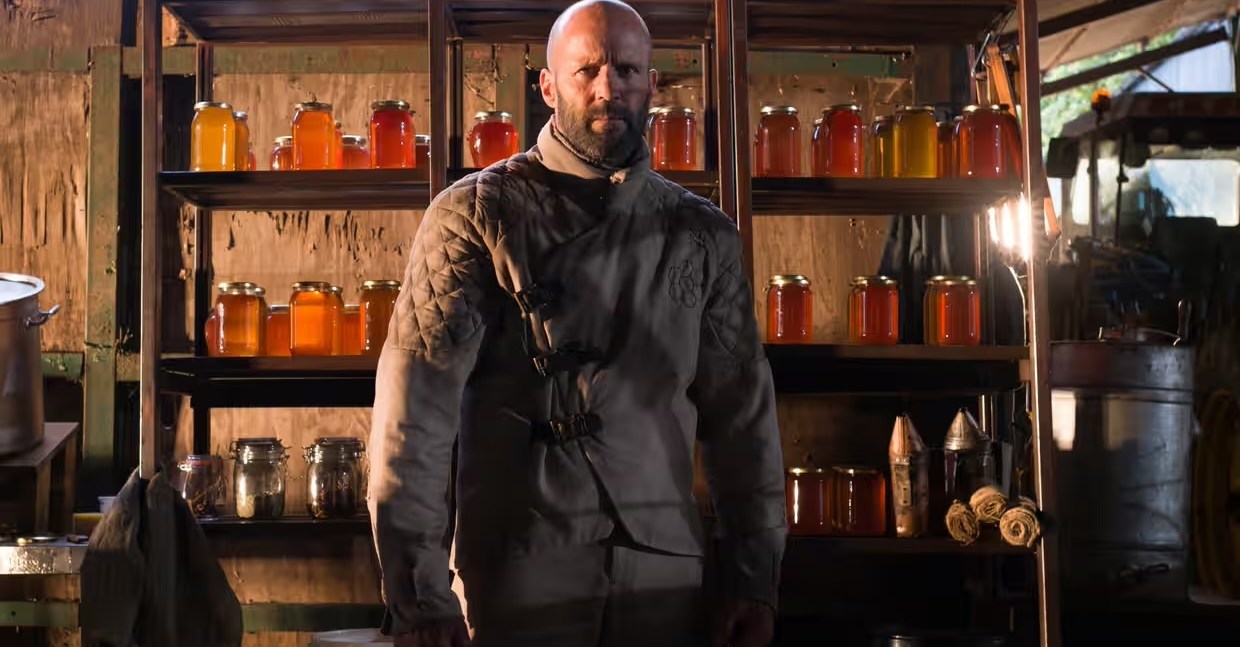 A beekeeper (Jason Statham) stands in front of some honey in The Beekeeper
