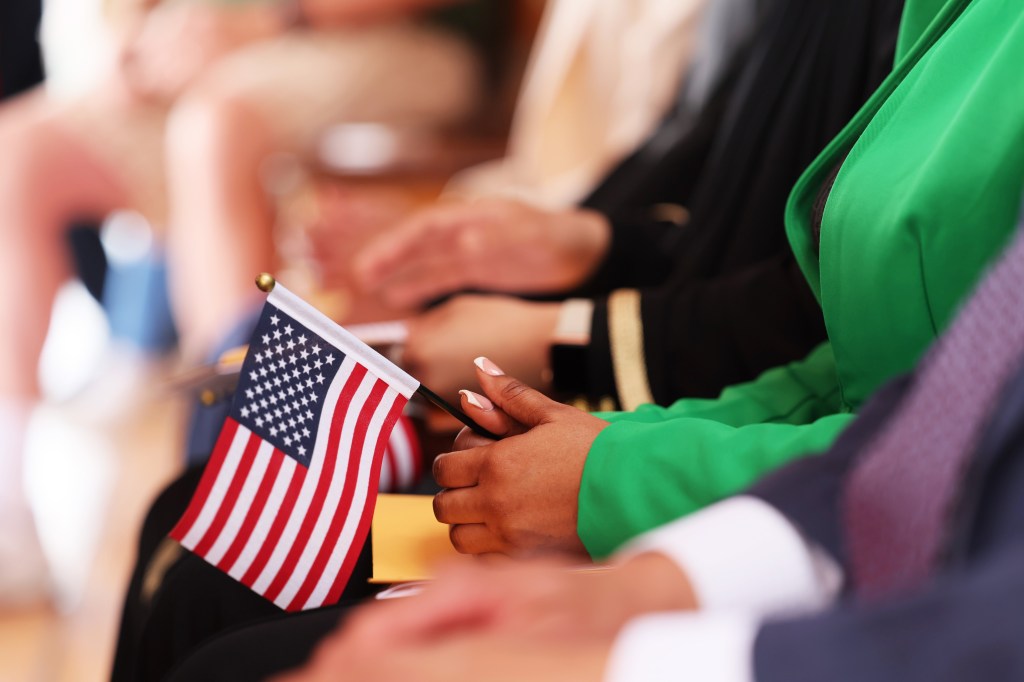 Person holding an American flag at a naturalization ceremony.