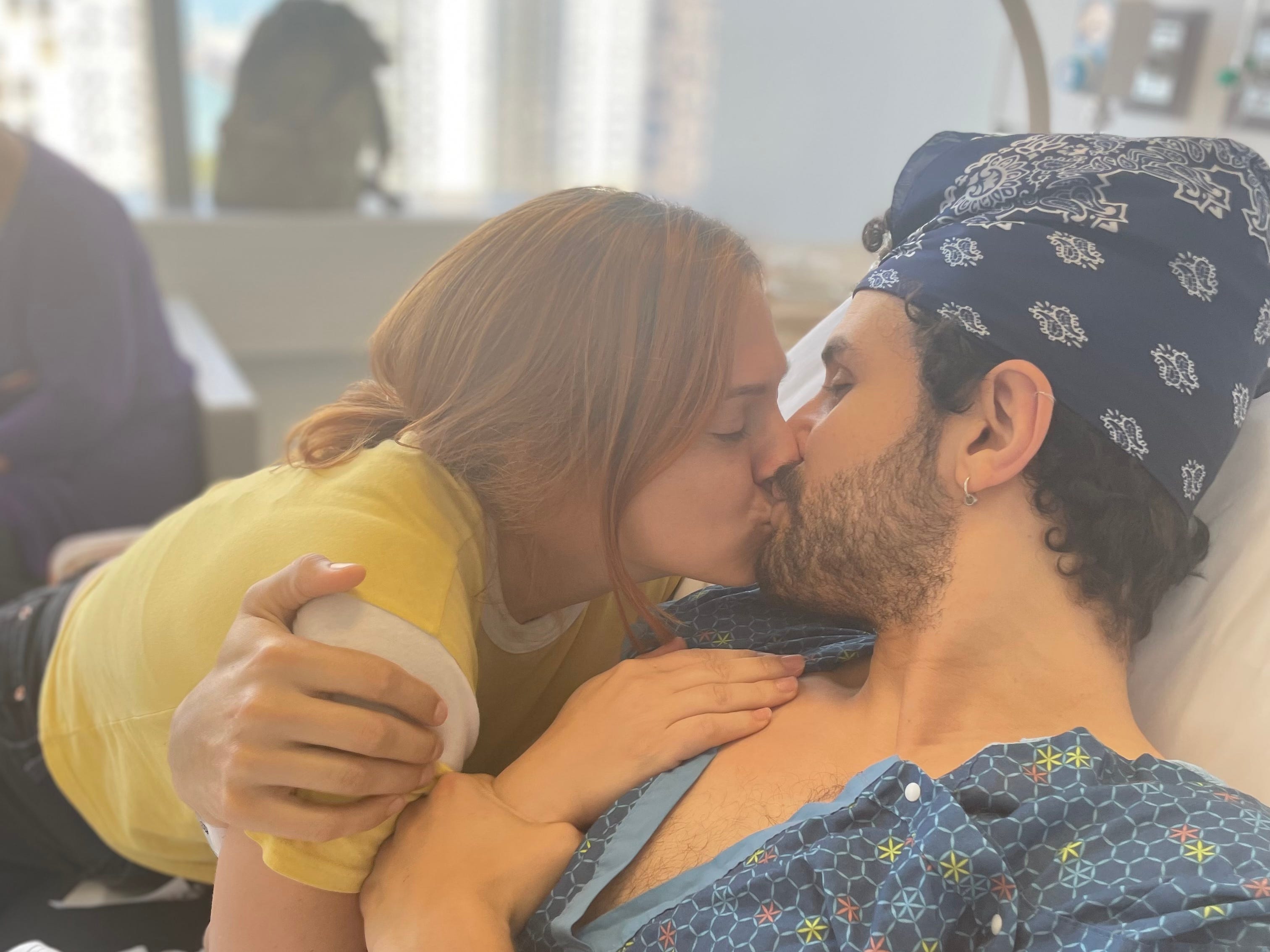 The author kissing her husband while he's in a hospital bed.