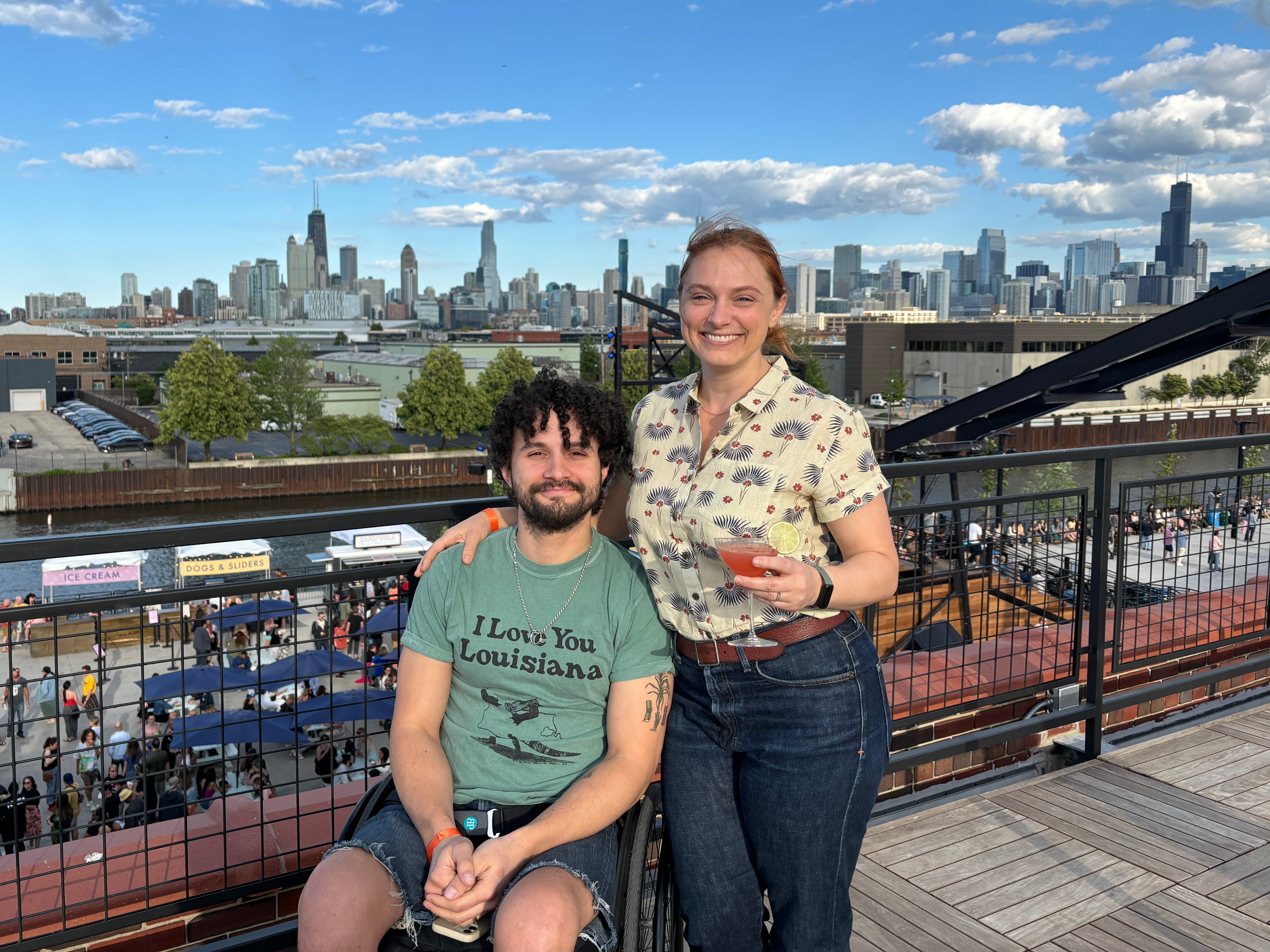 The author and her husband on a bridge overlooking a waterfront and a city skyline.