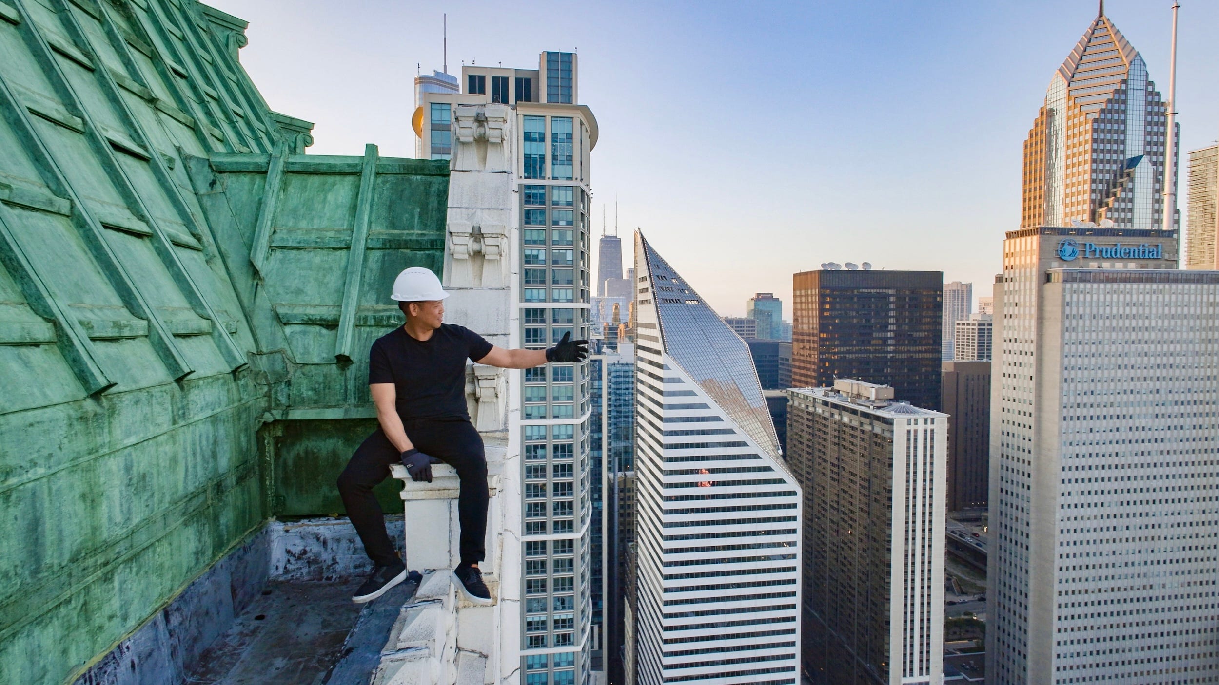 A man sitting on top of a skyscraper in Chicago.