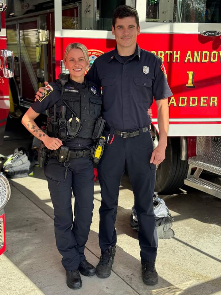 Photo of two North Andover first responders, a police officer and a firefighter, standing together in front of a firetruck.