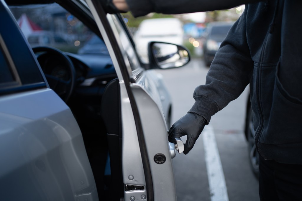 Close-up of a thief attempting to break into a car.
