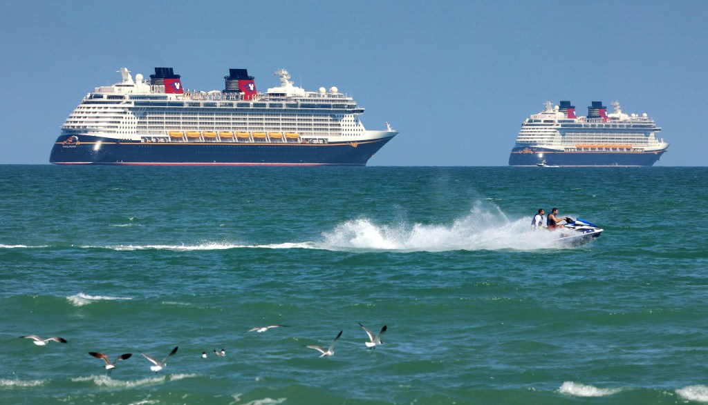 Jet skiers pass Disney Cruise Line ships at sea.