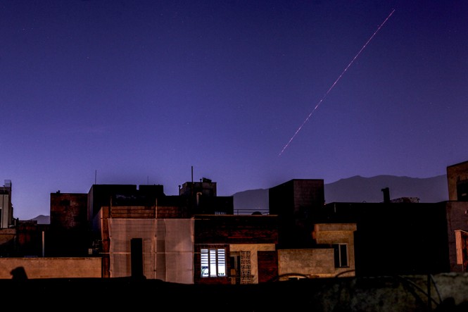 Iran's air defense systems operate to counter Israeli airstrikes in Tehran at night over city apartments.
