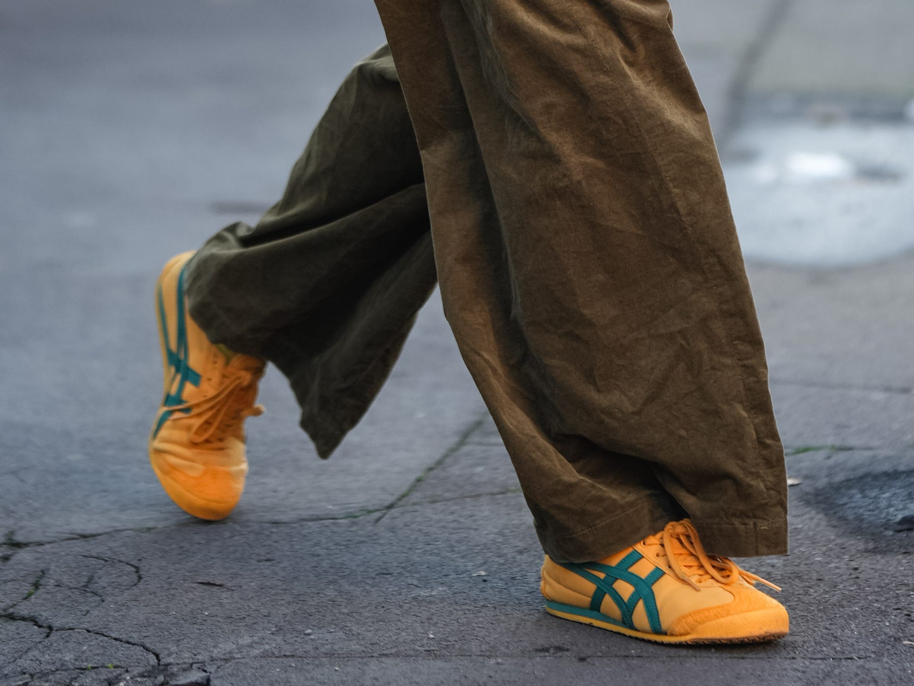 A woman wearing bright orange sneakers with green detailing. 
