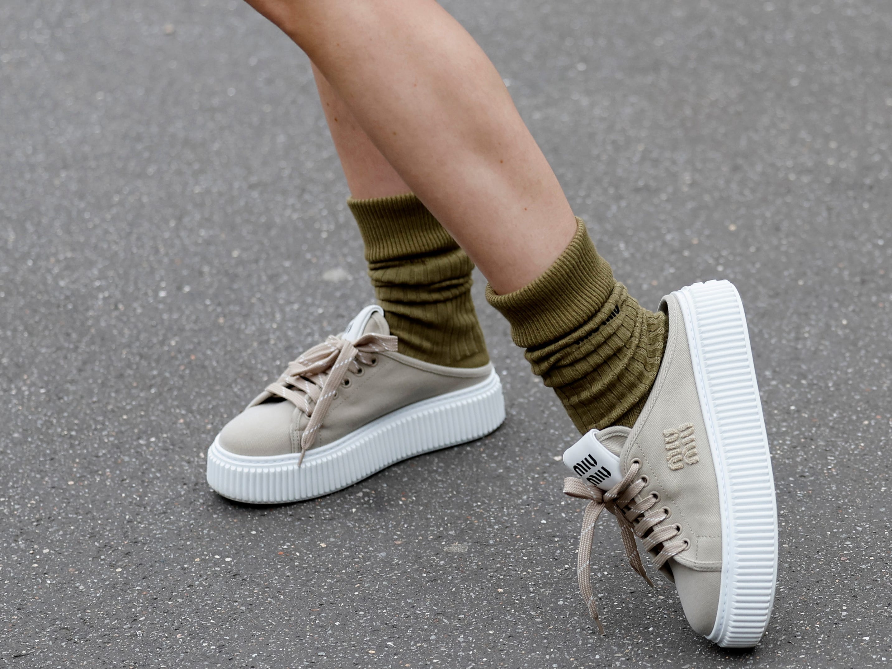 A woman wearing backless sneakers.