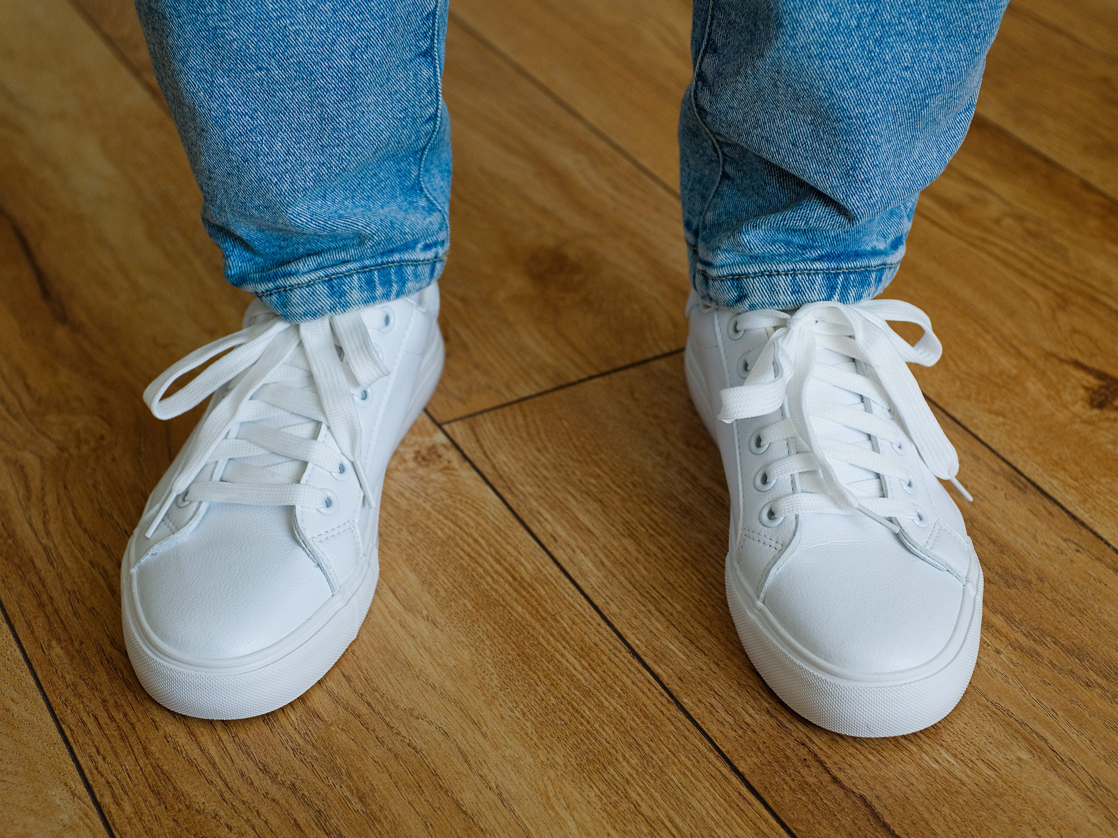 A person wearing jeans and all-white sneakers.