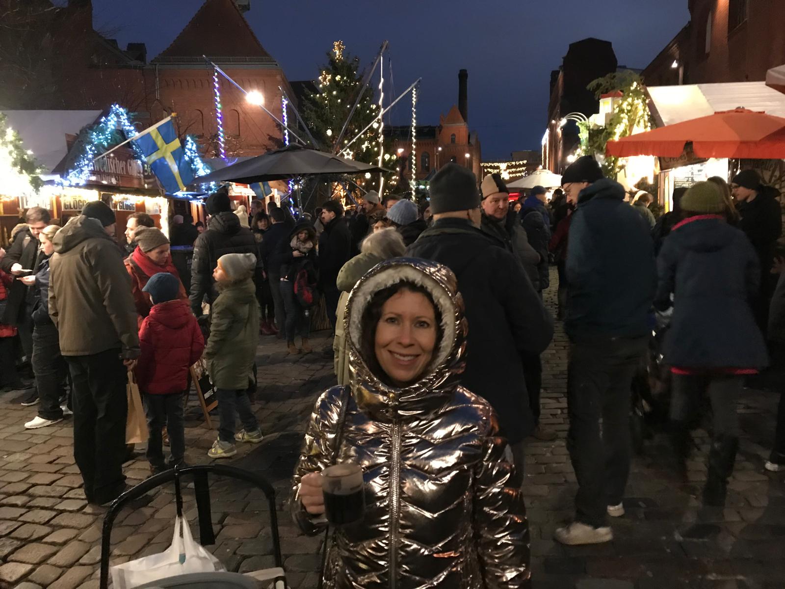 Author Liz Humphreys smiling in metallicjacket in dark in Berlin